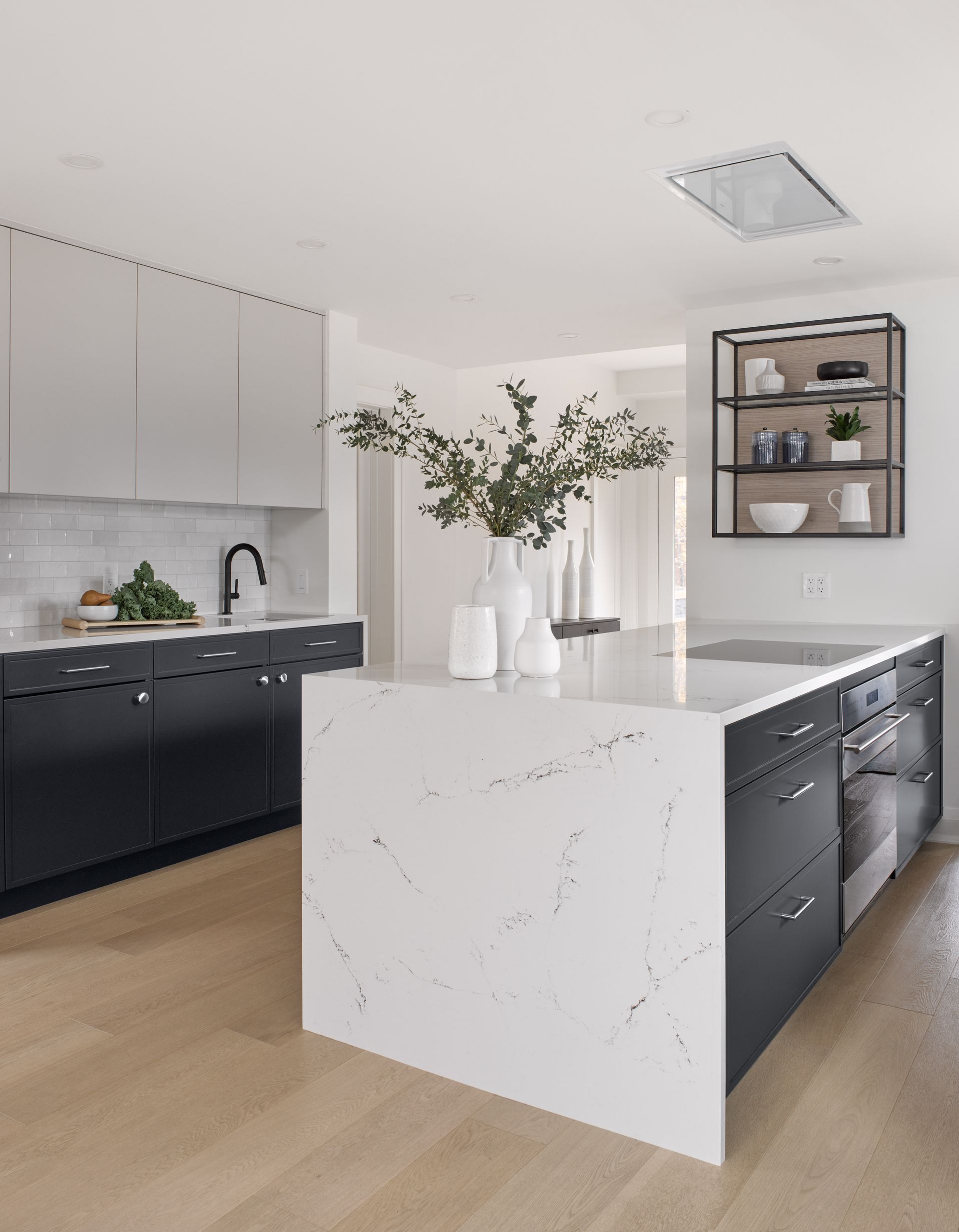 A kitchen with black cabinets and a large white island