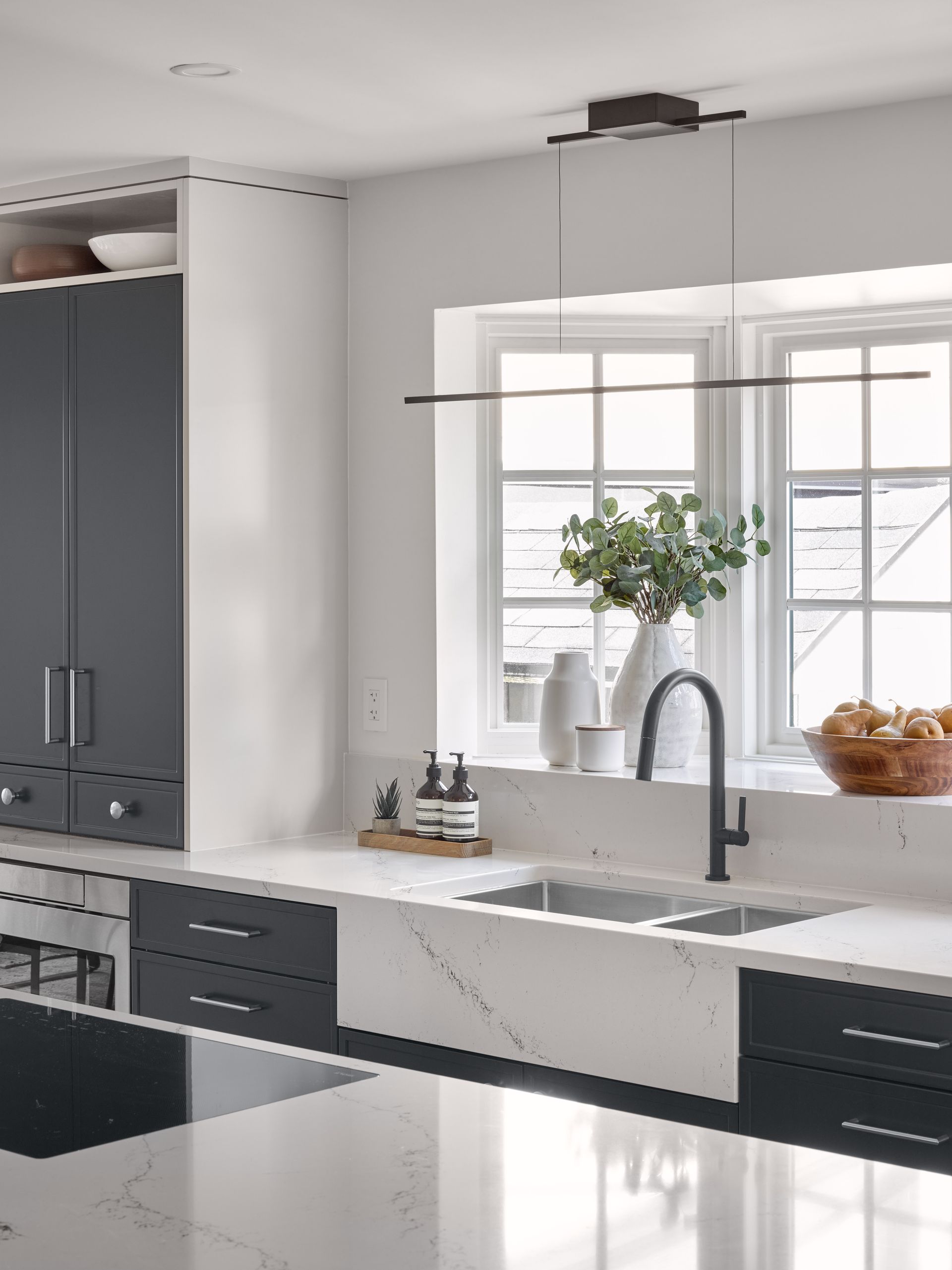 A kitchen with a sink , stove , cabinets and a window.