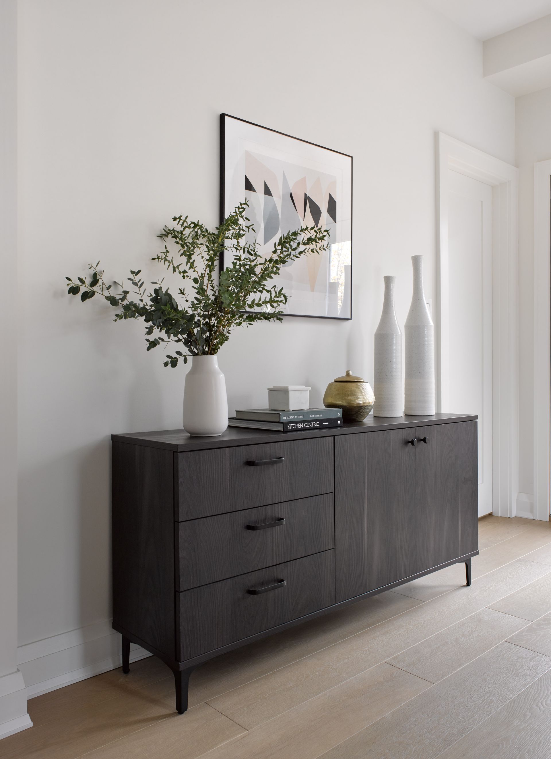 A dresser with a vase of flowers on top of it in a hallway.