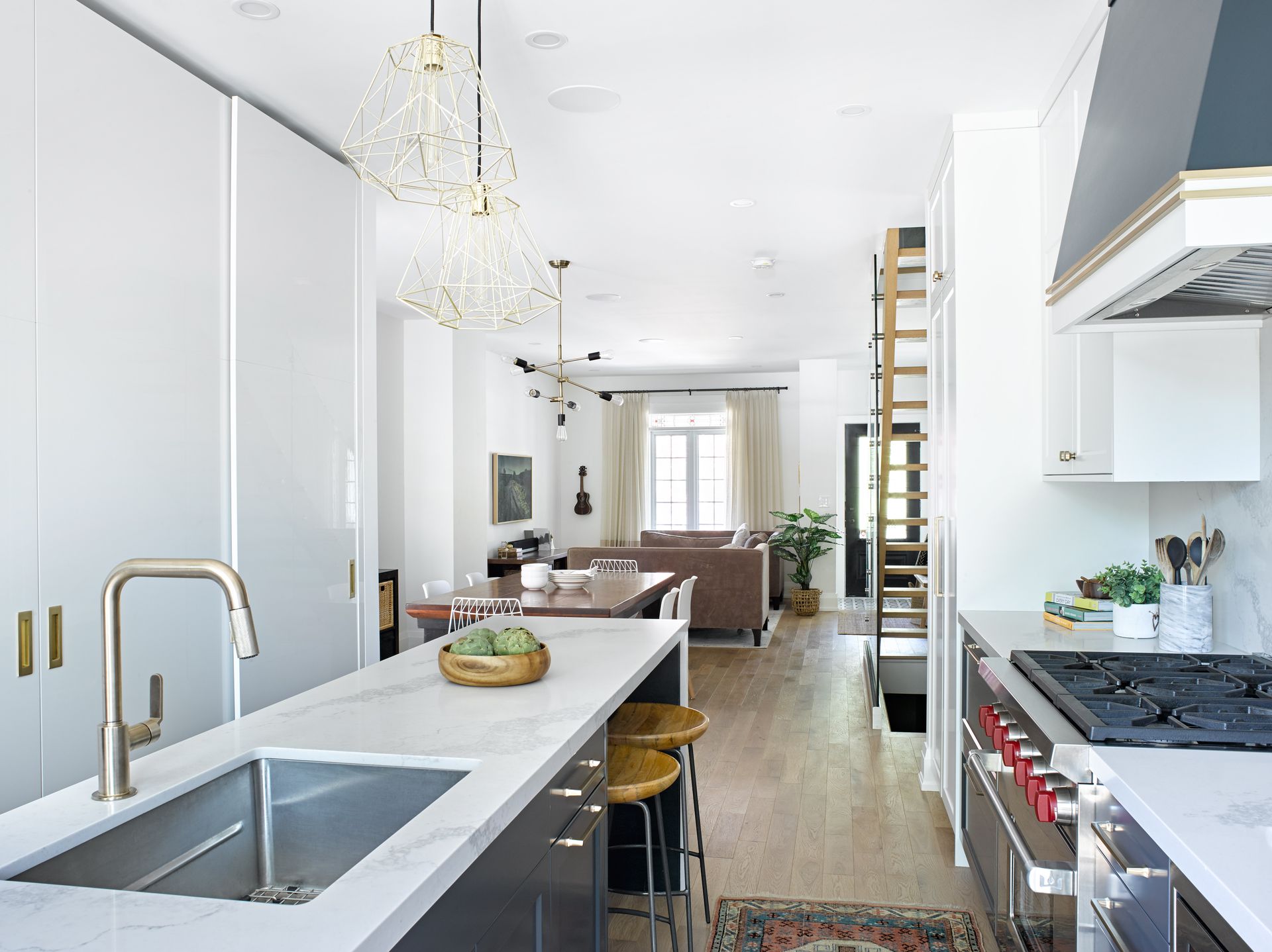 A kitchen with a sink , stove , oven and stools.