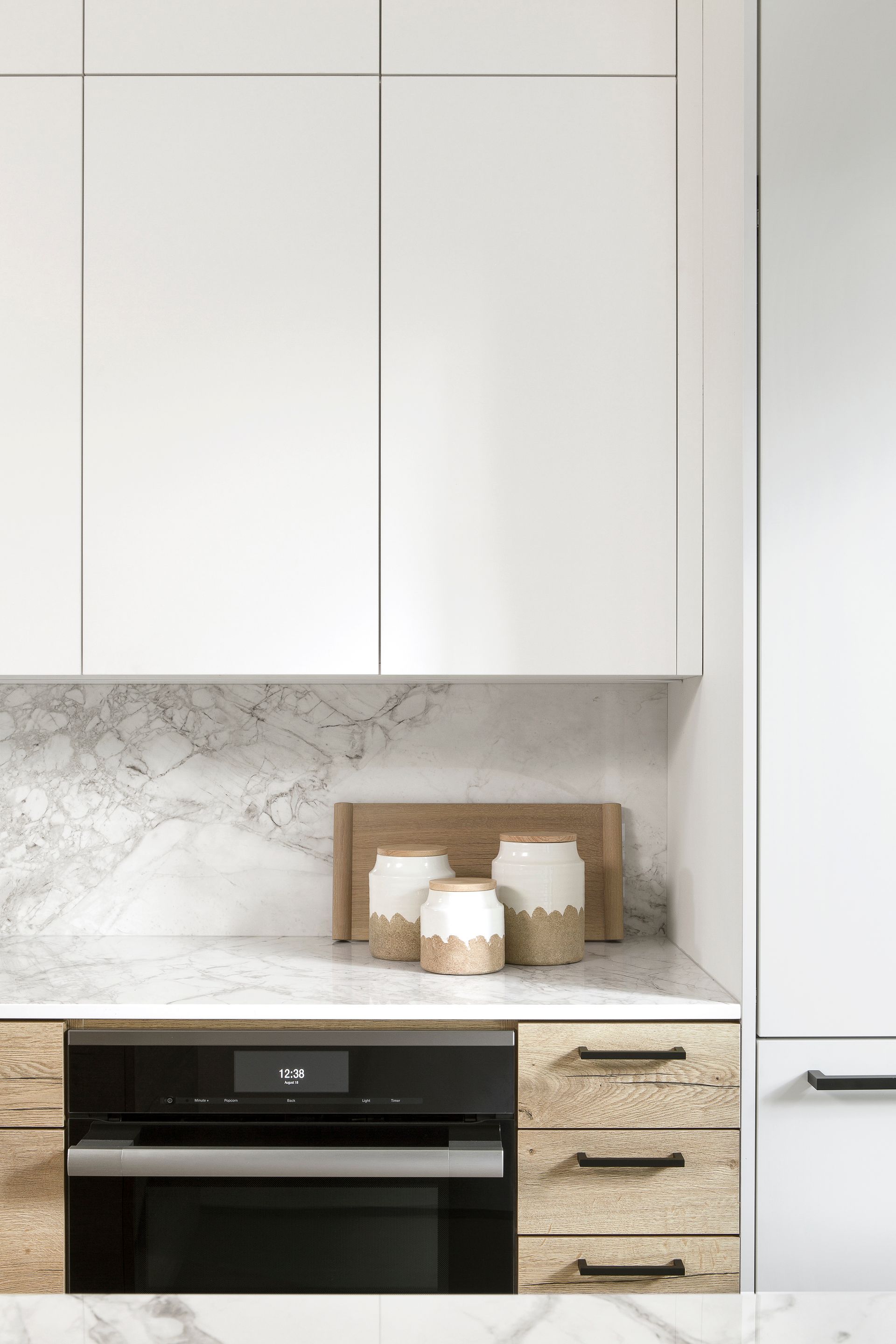 A kitchen with white cabinets and a black oven.