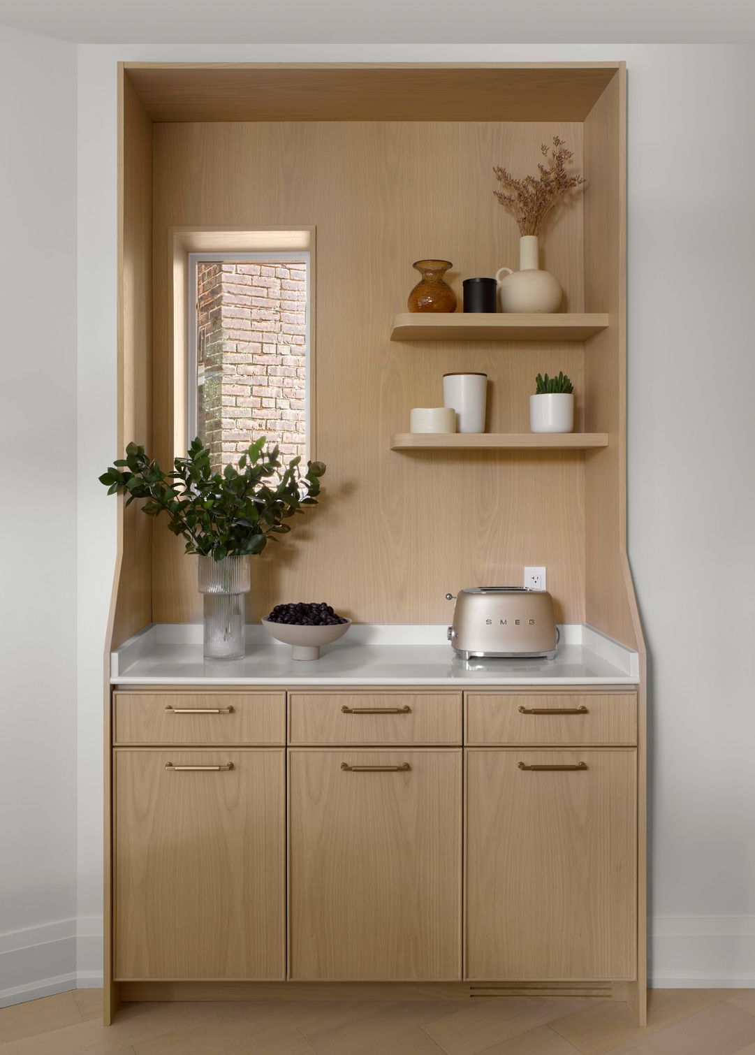 A kitchen with wooden cabinets , a toaster oven , and shelves.