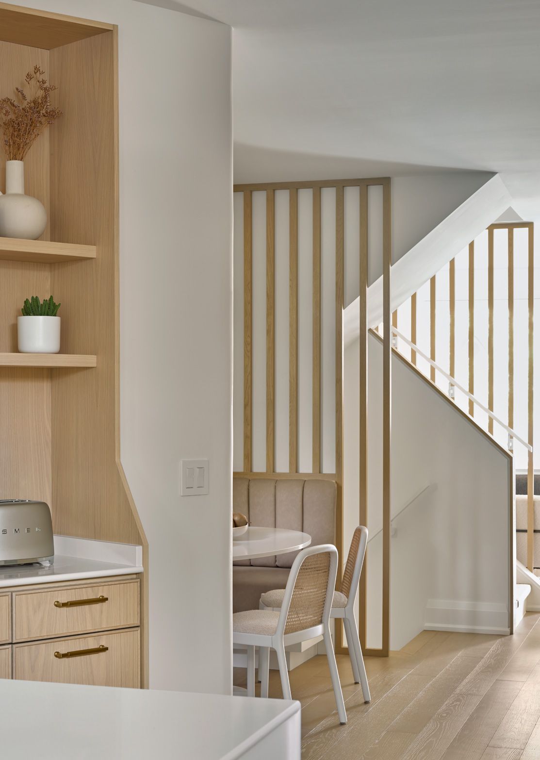 A kitchen with a table and chairs and a staircase in the background