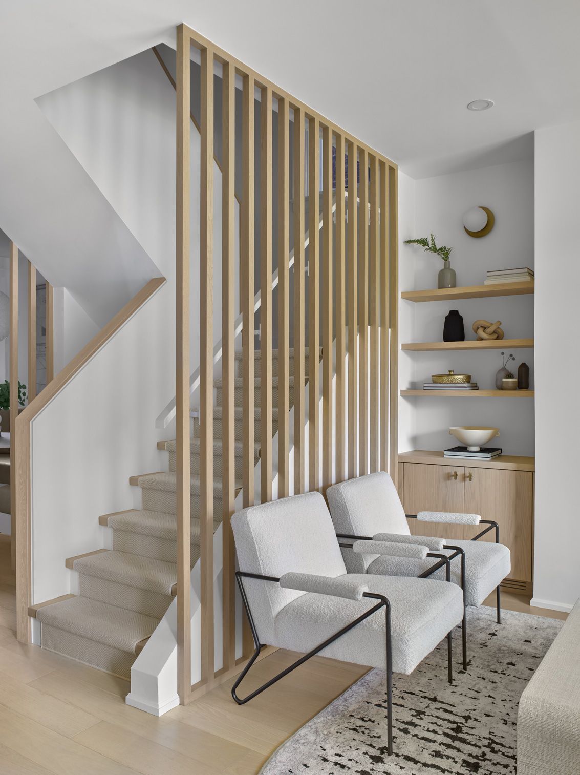 A living room with two chairs and a wooden staircase.