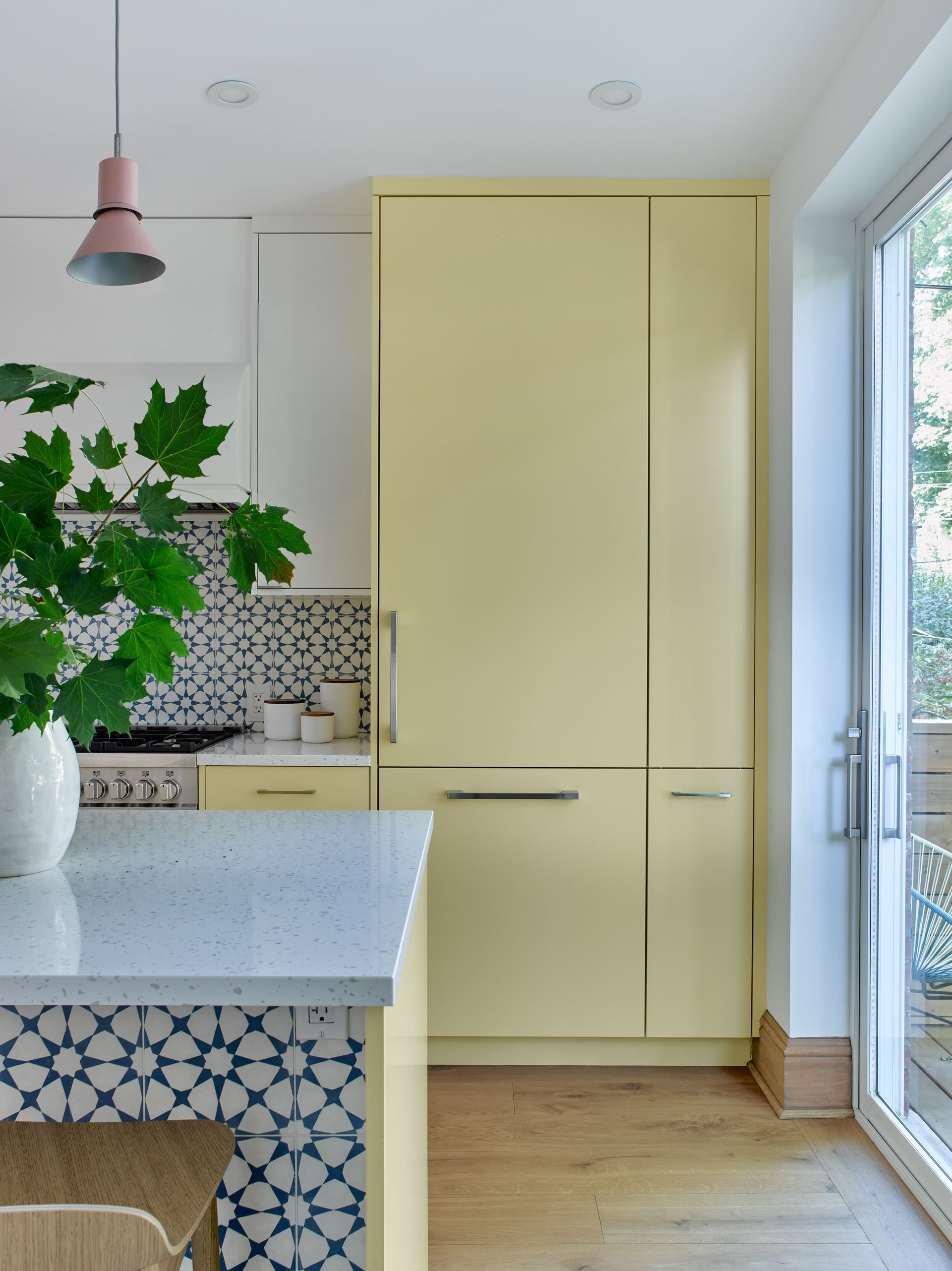 A kitchen with yellow cabinets and a plant on the counter