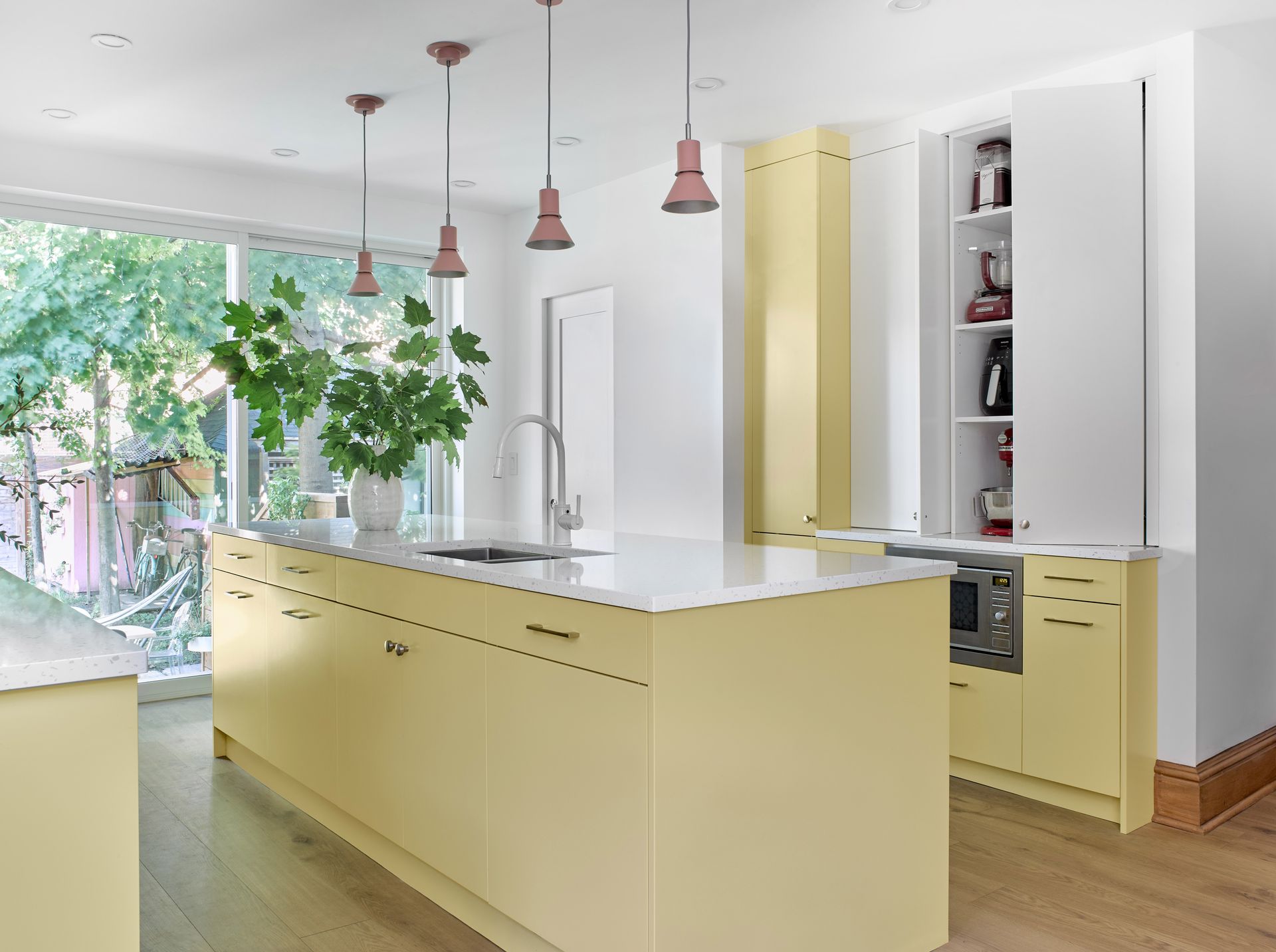 A kitchen with yellow cabinets and white counter tops.