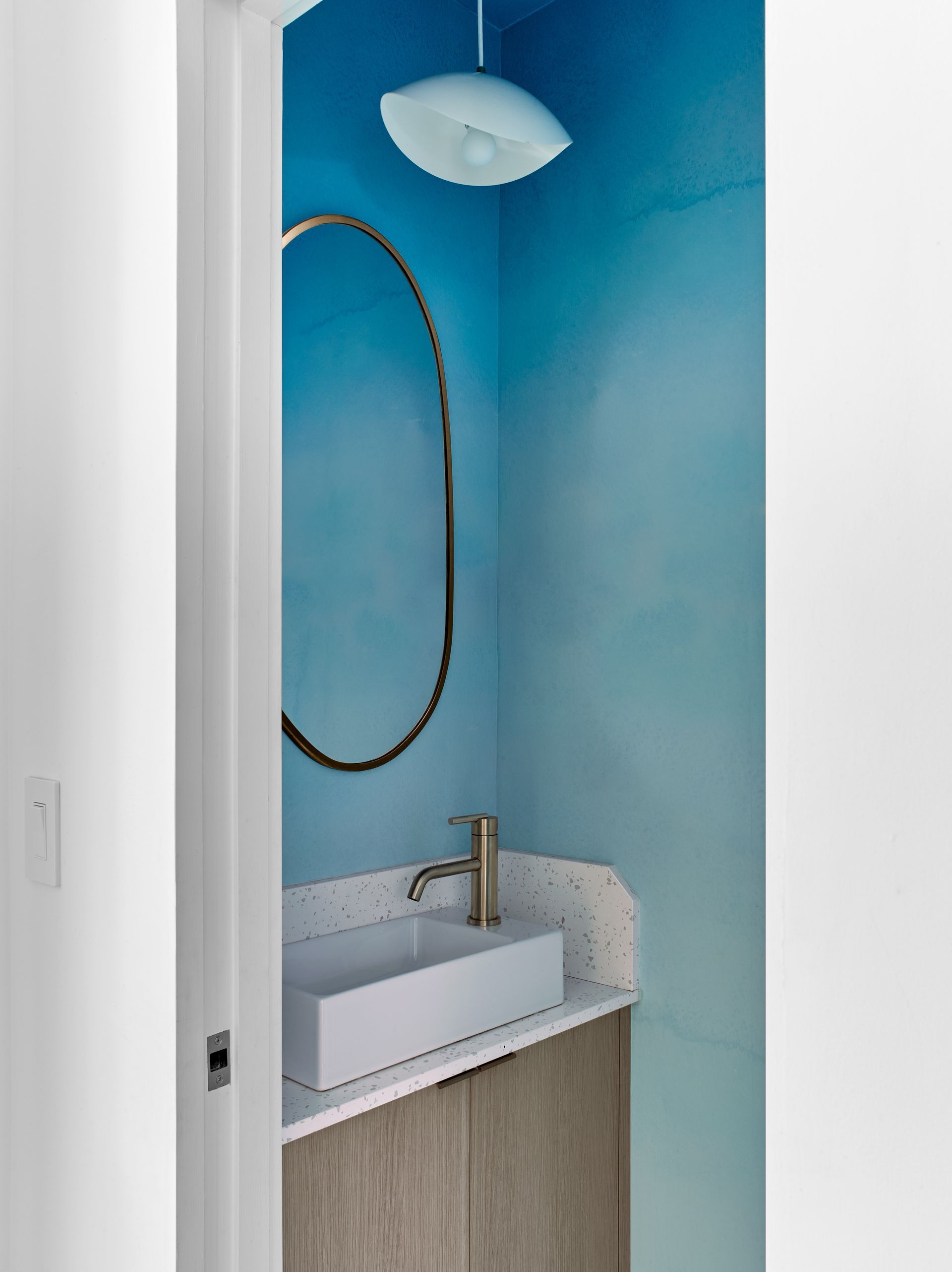 A bathroom with blue walls and a sink and mirror