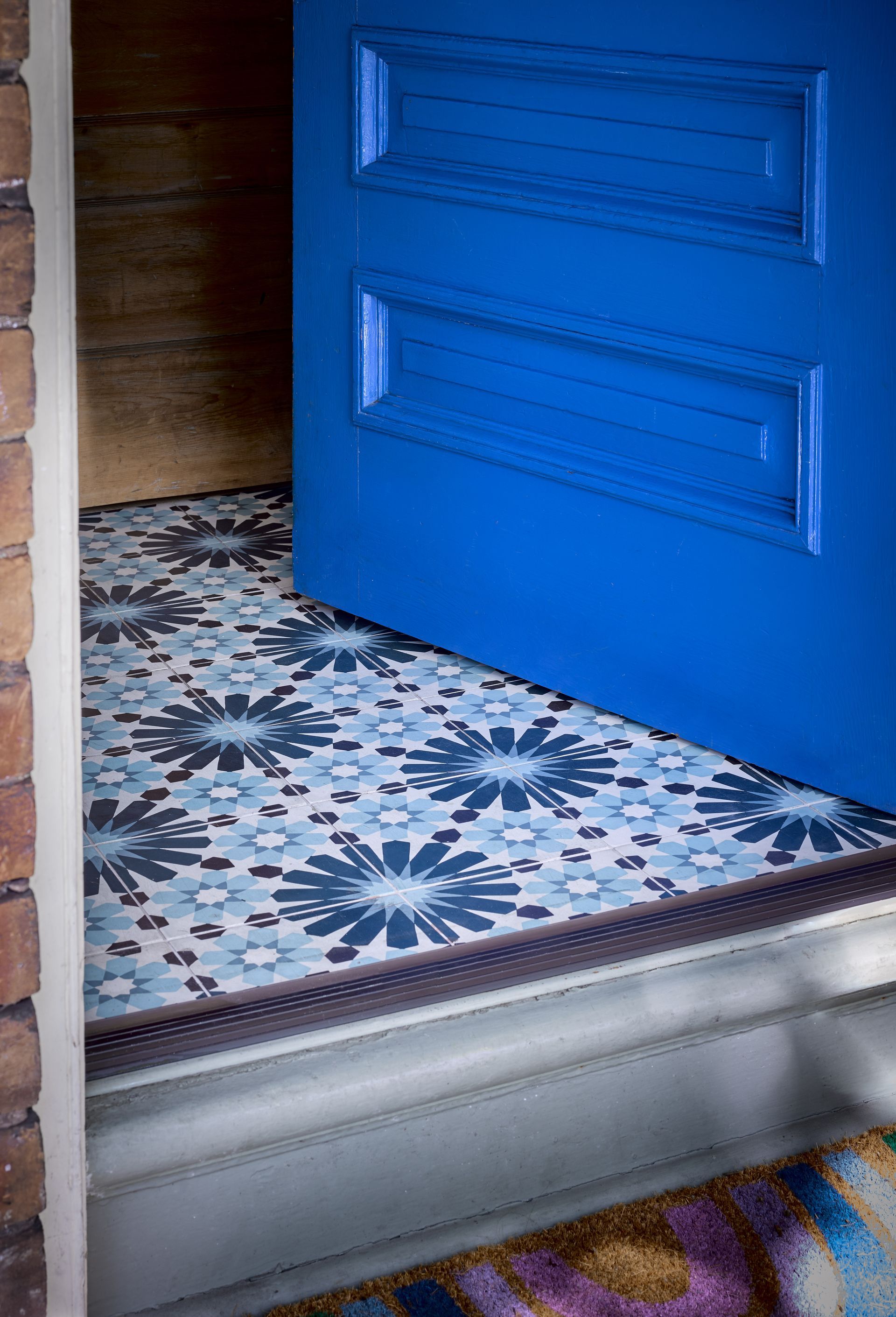 A blue door is open to a blue and white tiled floor.