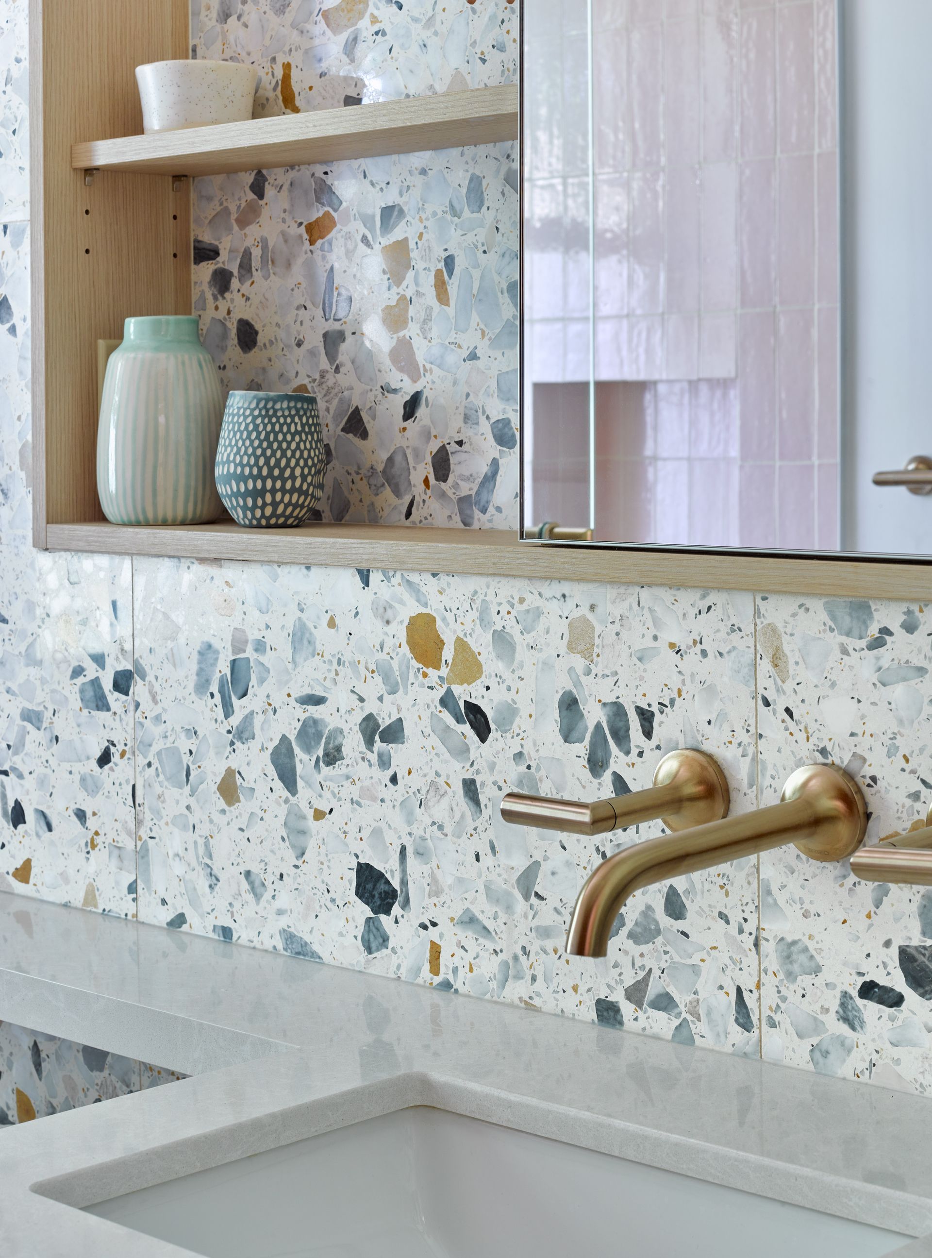 A bathroom with a sink , mirror and terrazzo tiles.