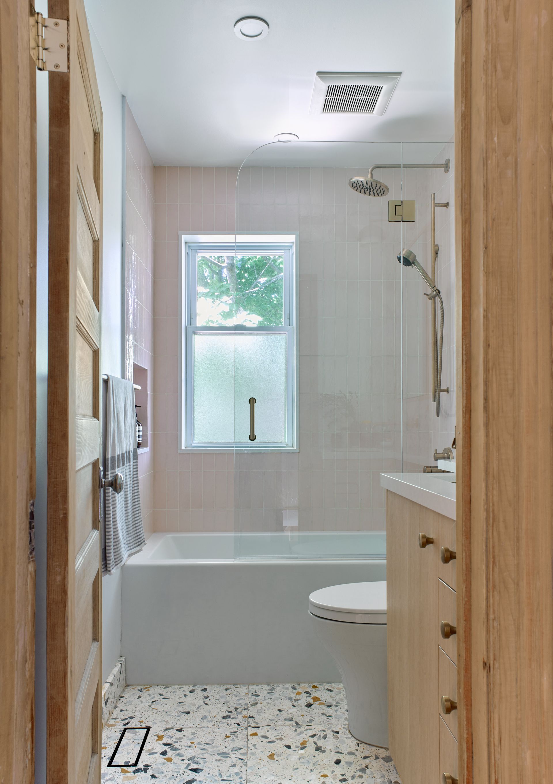A bathroom with a tub , toilet , sink and window.