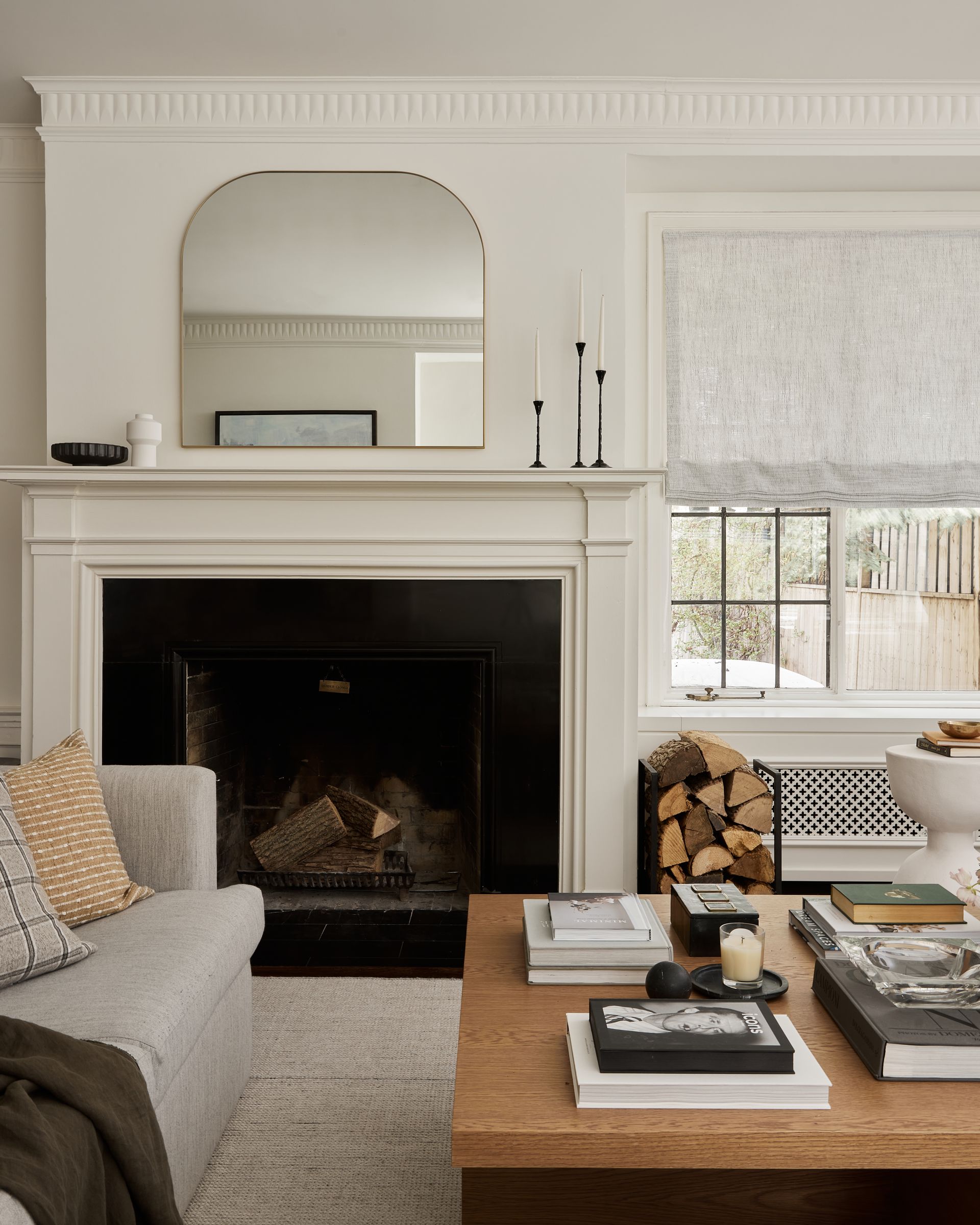 A living room with a fireplace , couch , coffee table and mirror.