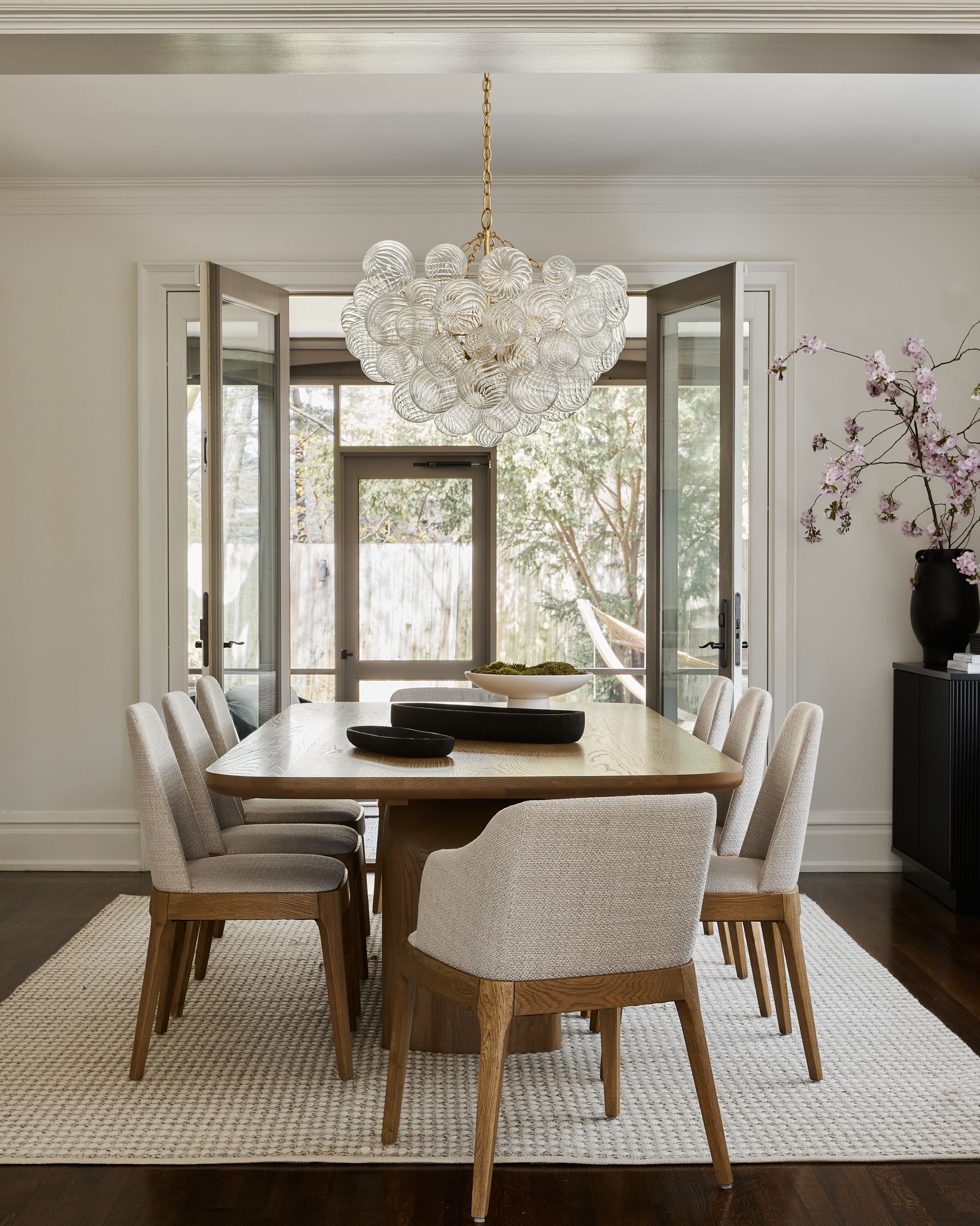 A dining room with a table and chairs and a chandelier hanging from the ceiling.