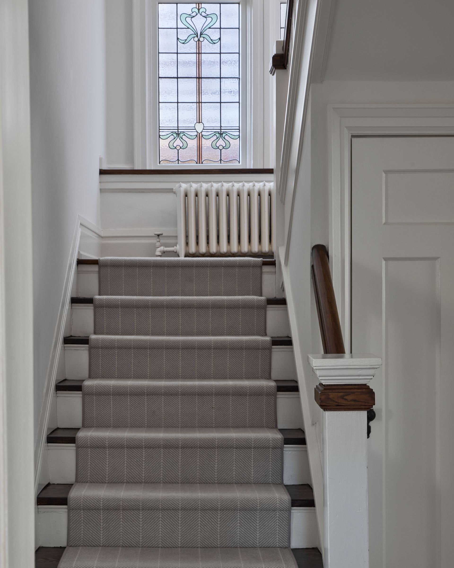 A staircase with a carpet on the steps and a window in the background
