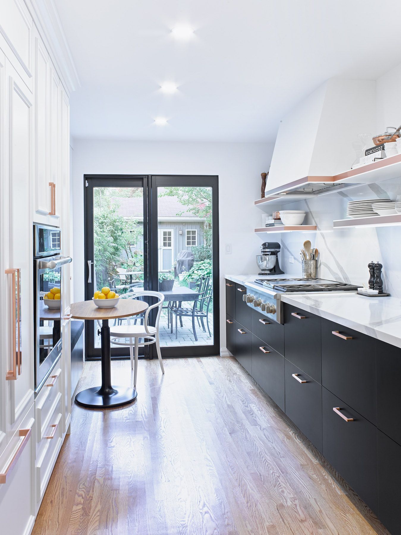 A kitchen with black cabinets , a stove , a table and chairs.