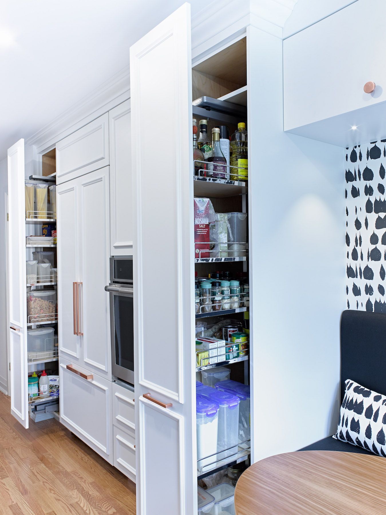 A kitchen with white cabinets , a table , and a pantry.
