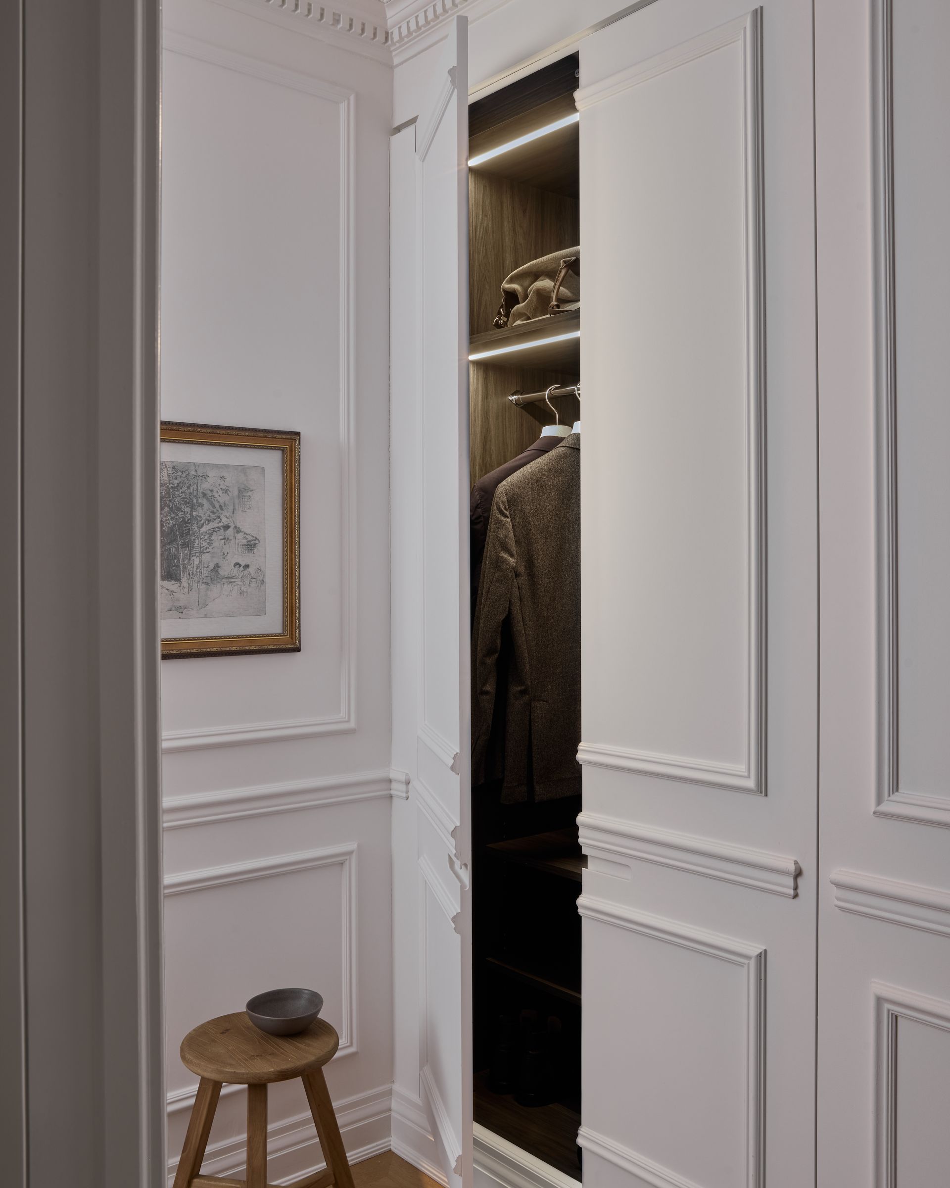 A walk in closet with a stool and a picture on the wall.