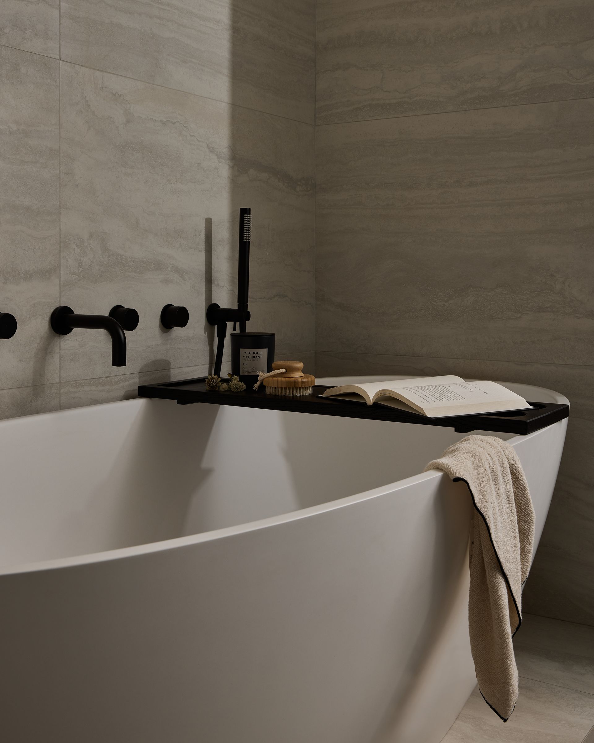 A bathtub with a towel and a book on it in a bathroom.