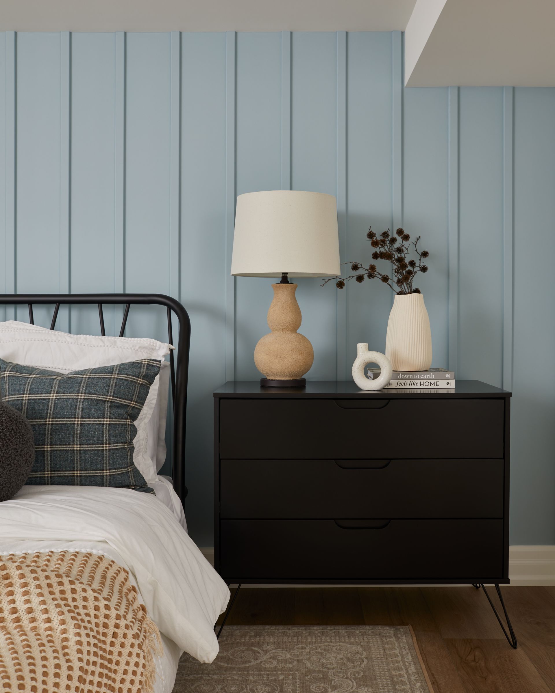 A bedroom with a bed , nightstand , lamp and blue walls