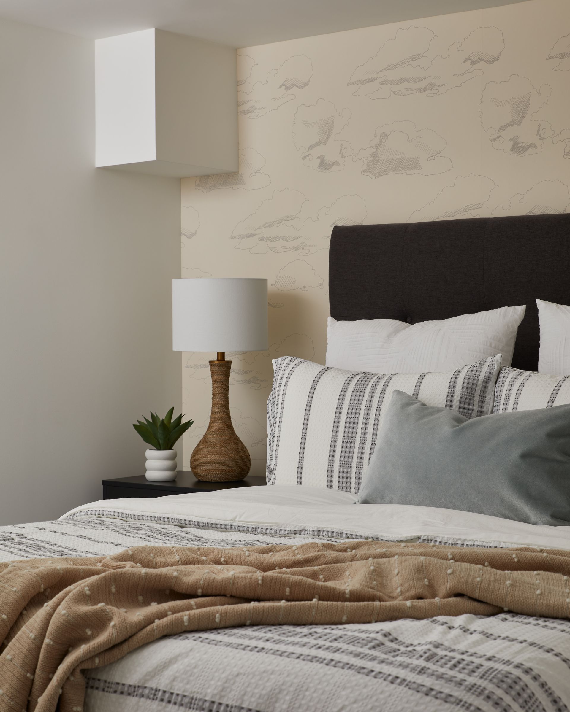 A bedroom with a bed and a lamp on the nightstand