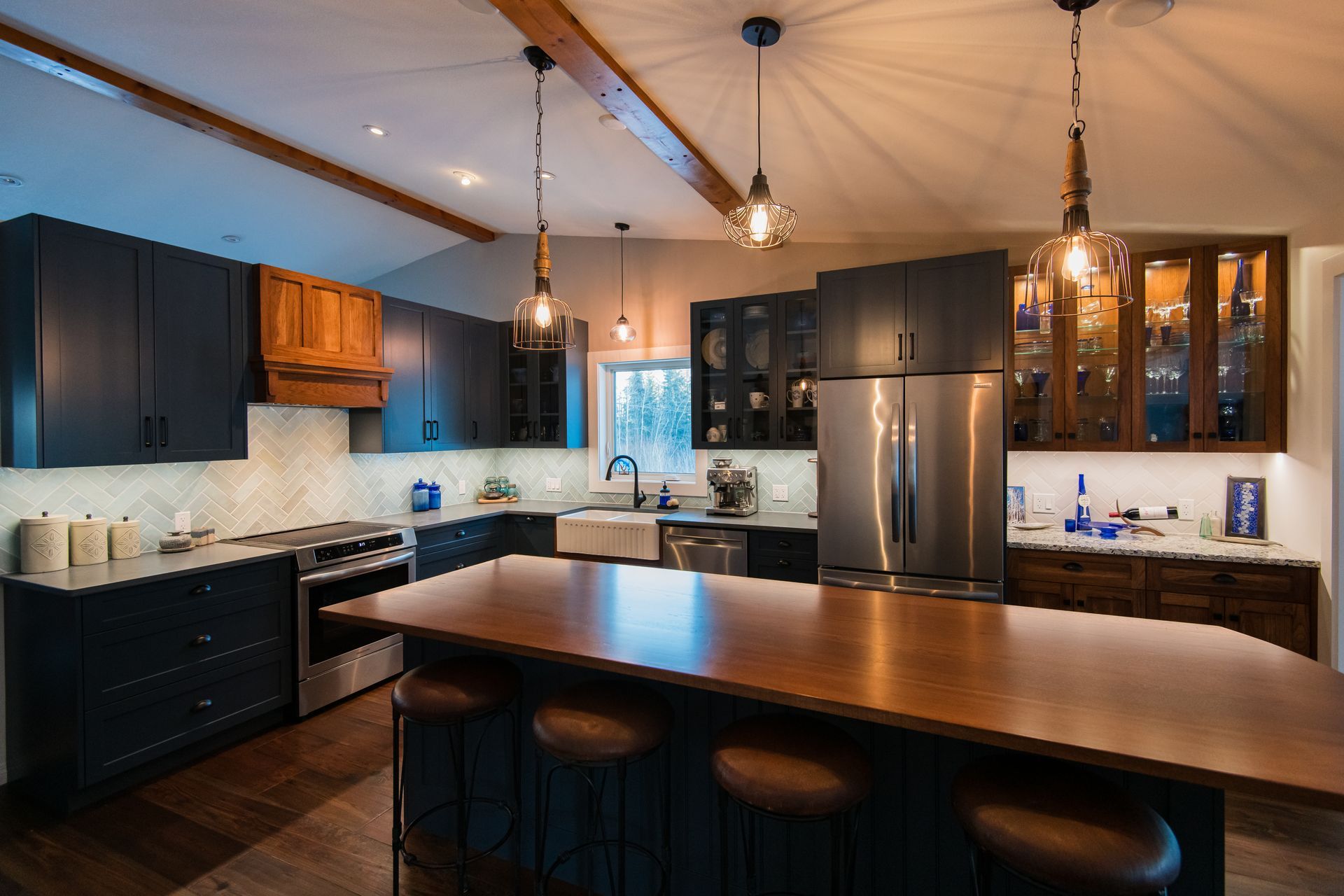 Modern kitchen with dark cabinets, stainless steel fridge, white backsplash, and a large wooden island
