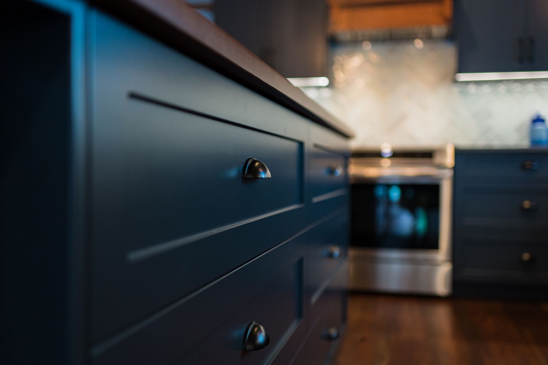 Blue kitchen cabinets beside a stainless steel oven in a modern kitchen