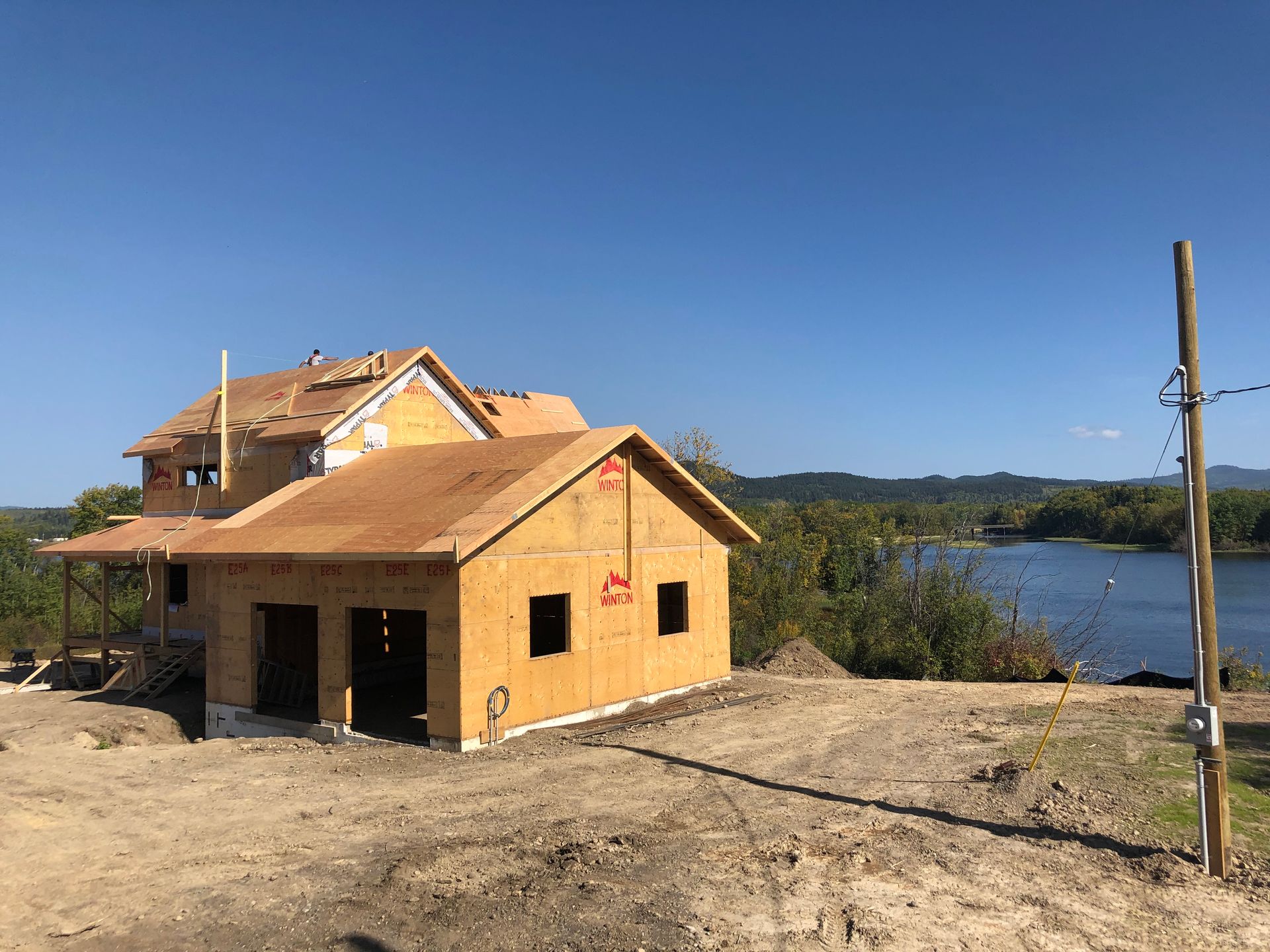 Unfinished yellow house under construction near a lake on a sunny day