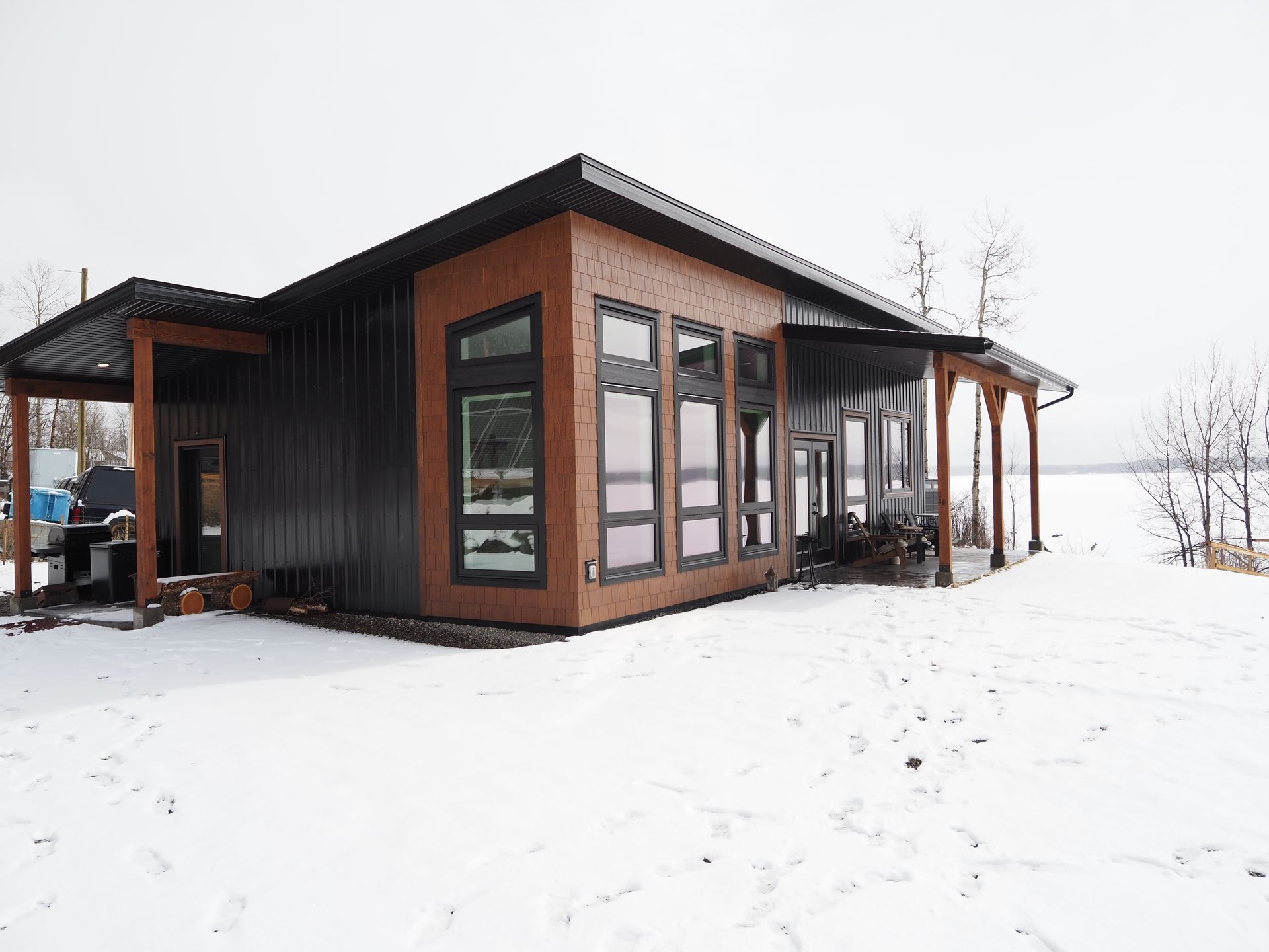 Modern black-and-wood cabin in a snowy landscape under an overcast sky