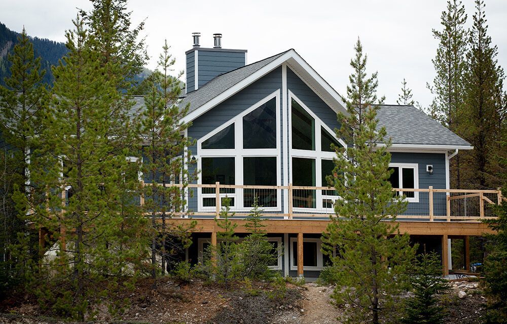 Modern house with large glass windows and a wooden deck among trees and rocks