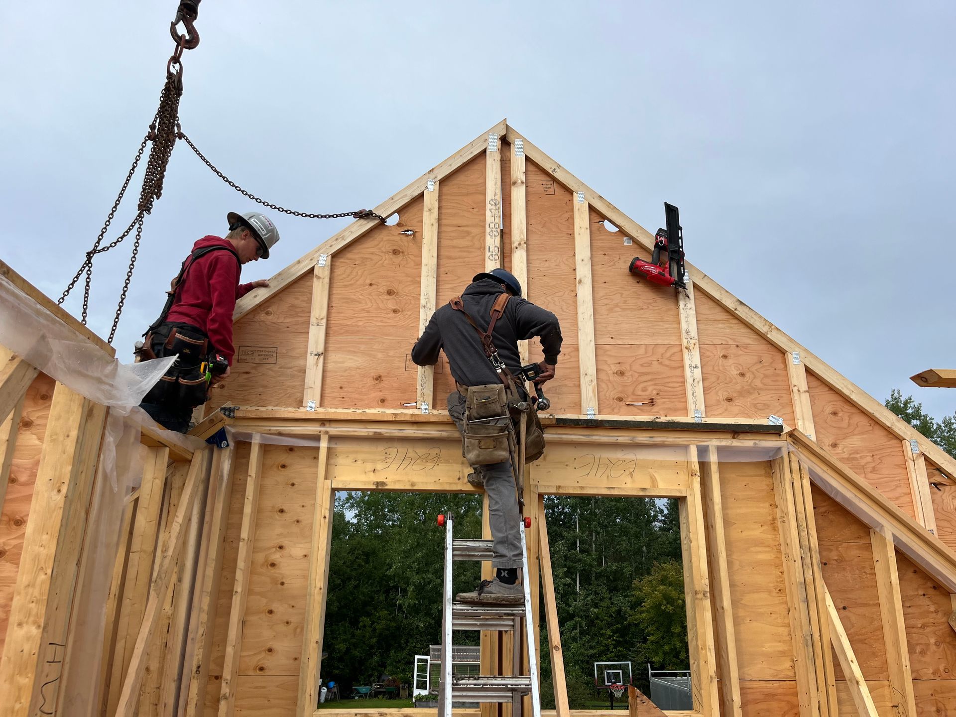 Workers framing a wooden house with ladders on a construction site