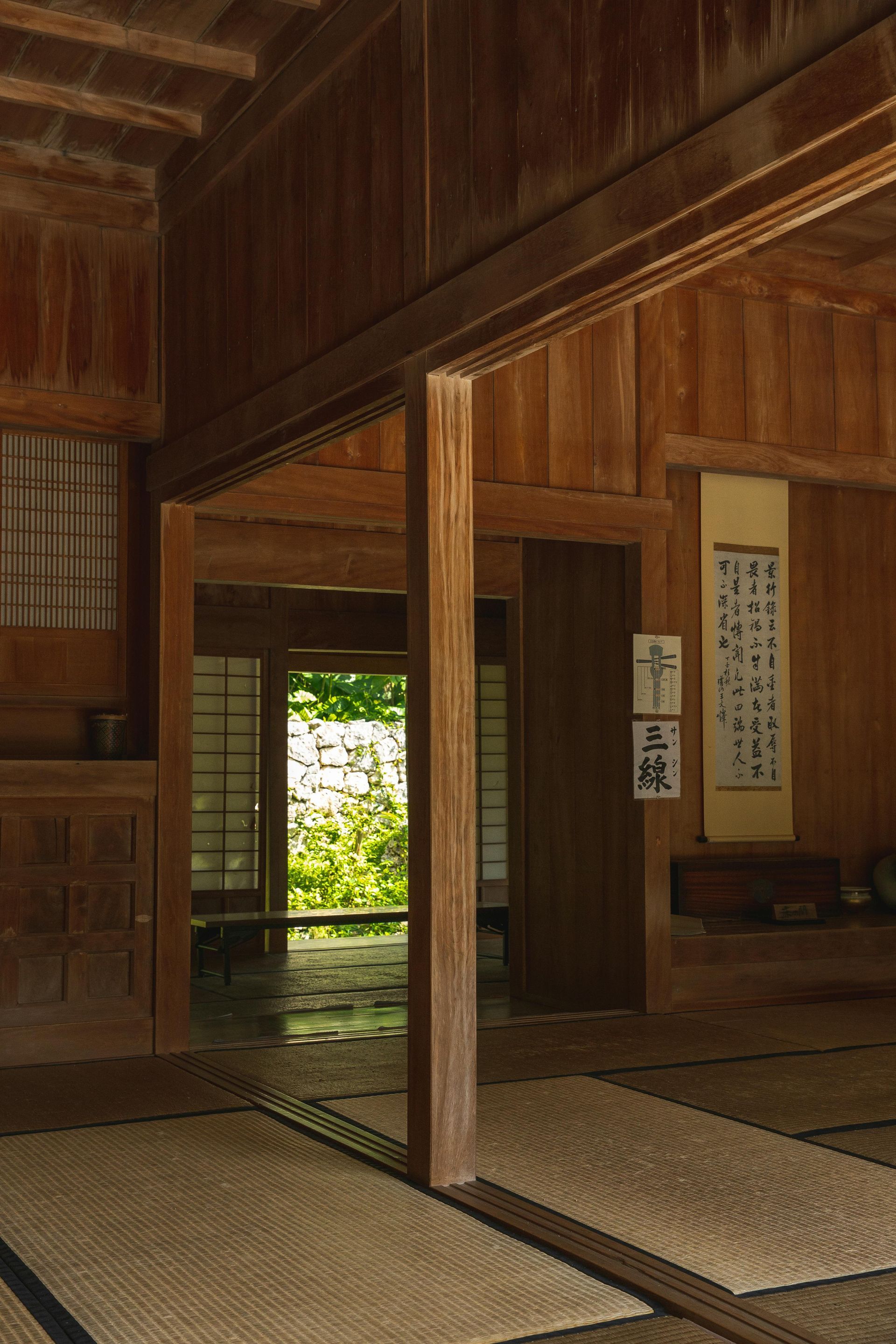 Traditional Japanese wooden room with tatami mats and a view of a bright garden through an open doorway