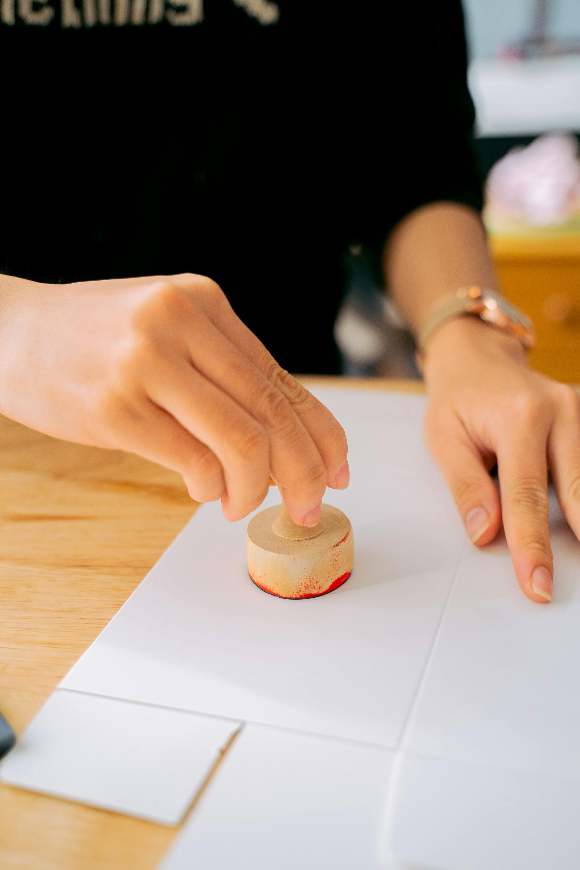 Hands placing a small macaron on white paper at a table