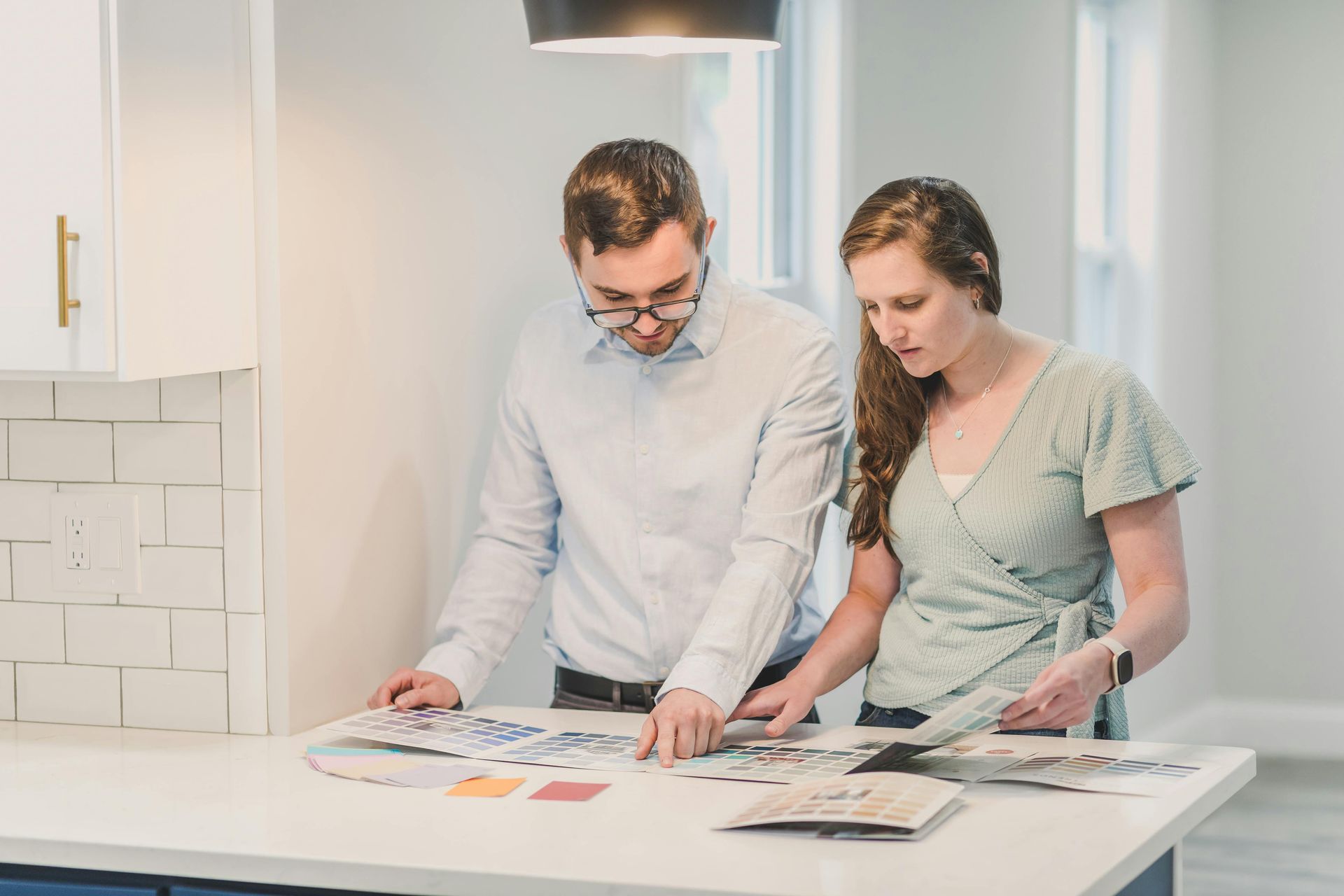 Two people reviewing printed designs on a table in a bright office