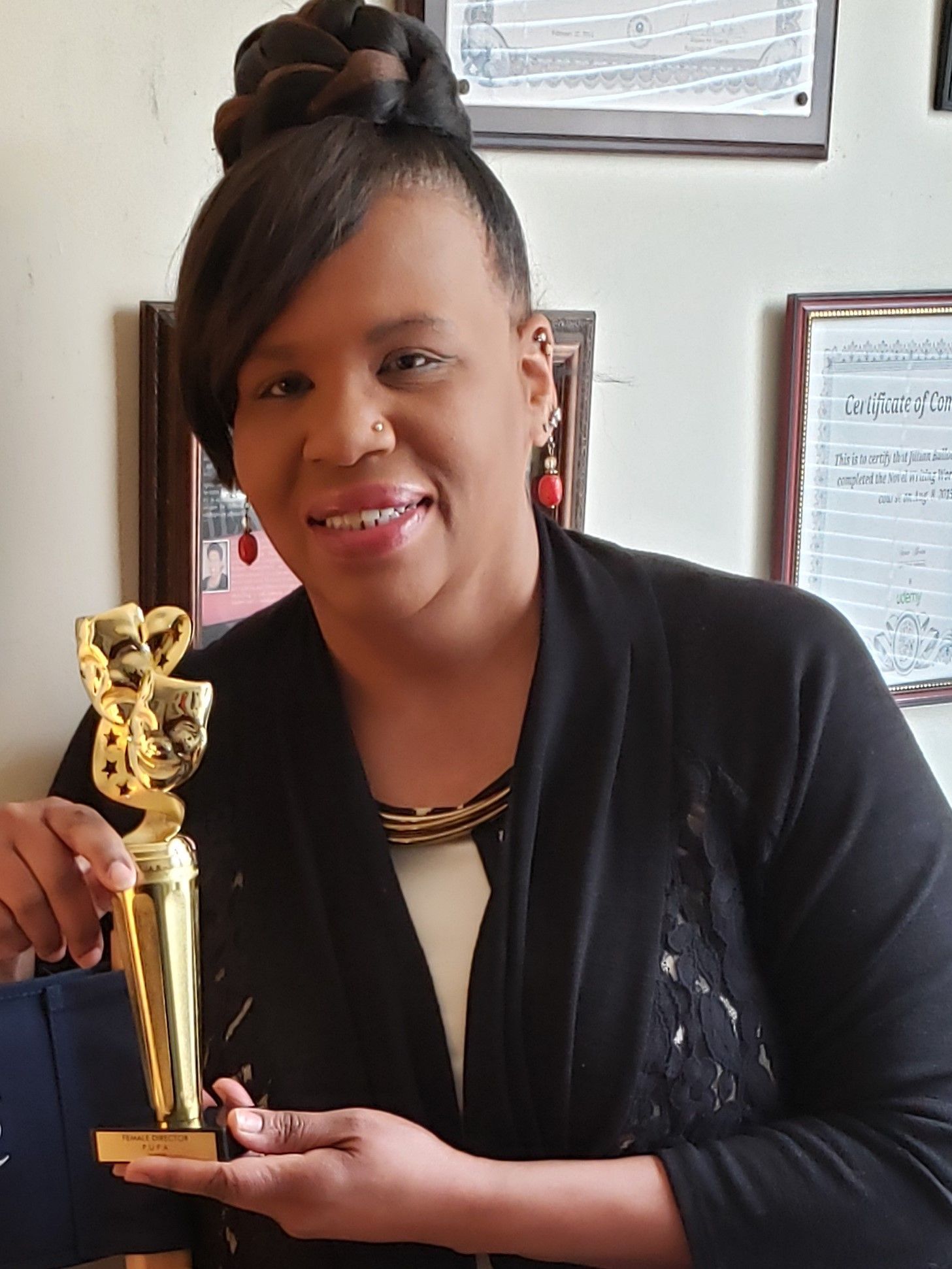 Jillian Bullock smiling while holding a gold statuette award in her office