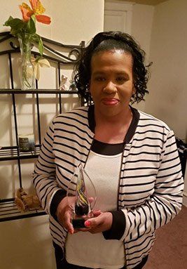 Jillian Bullock smiling while holding a crystal award