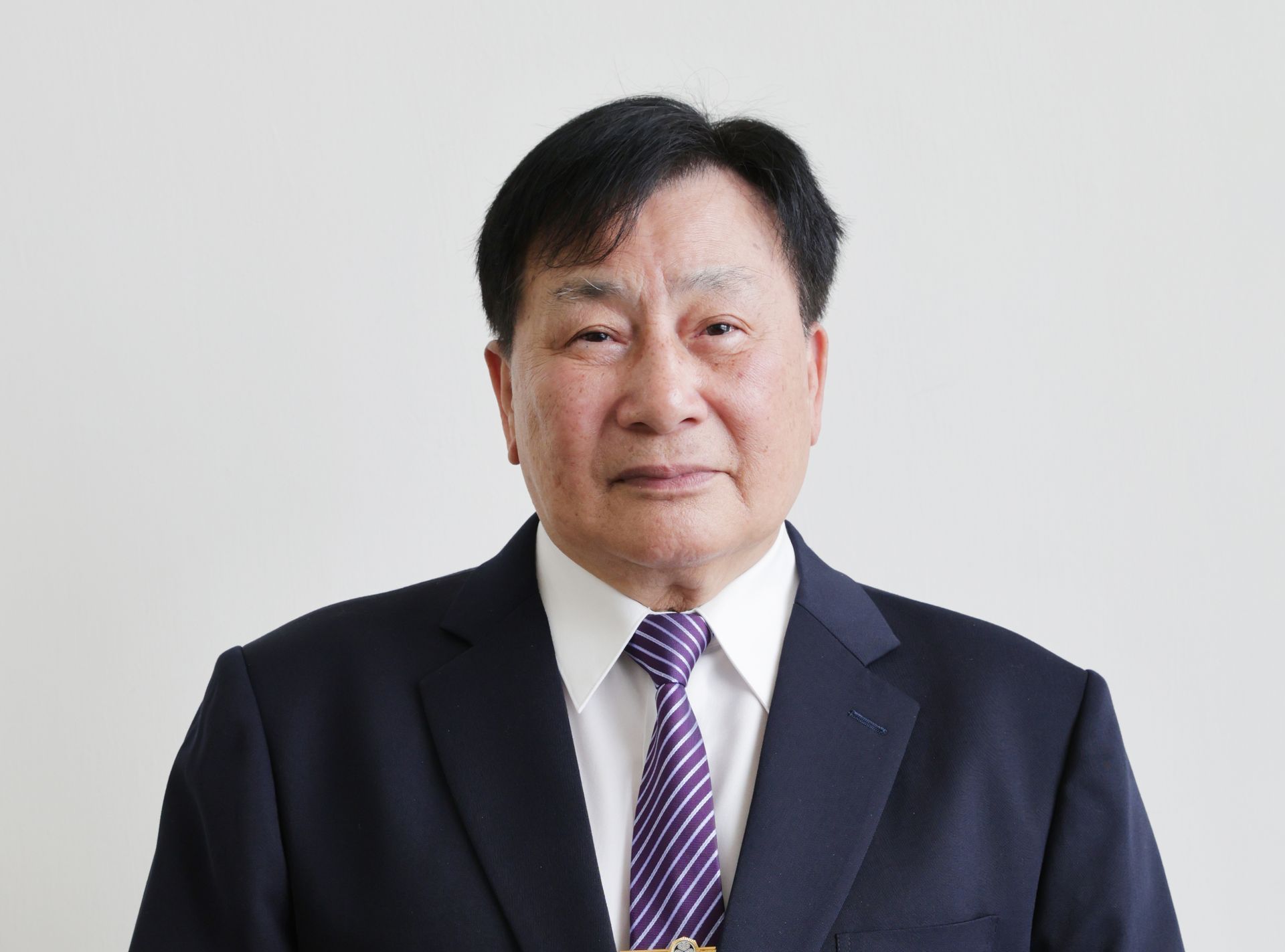 一名身穿黑色夾克的男子正拿著麥克風講話。
