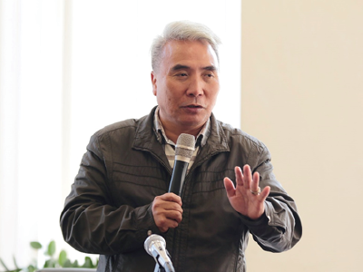 一名穿著夾克的男子拿著麥克風講話