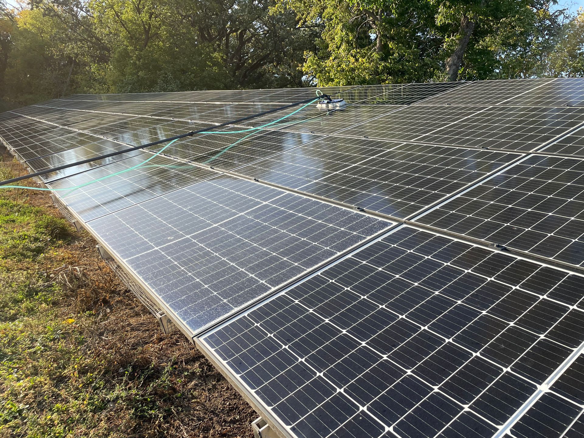 A row of solar panels sitting on top of a lush green field.