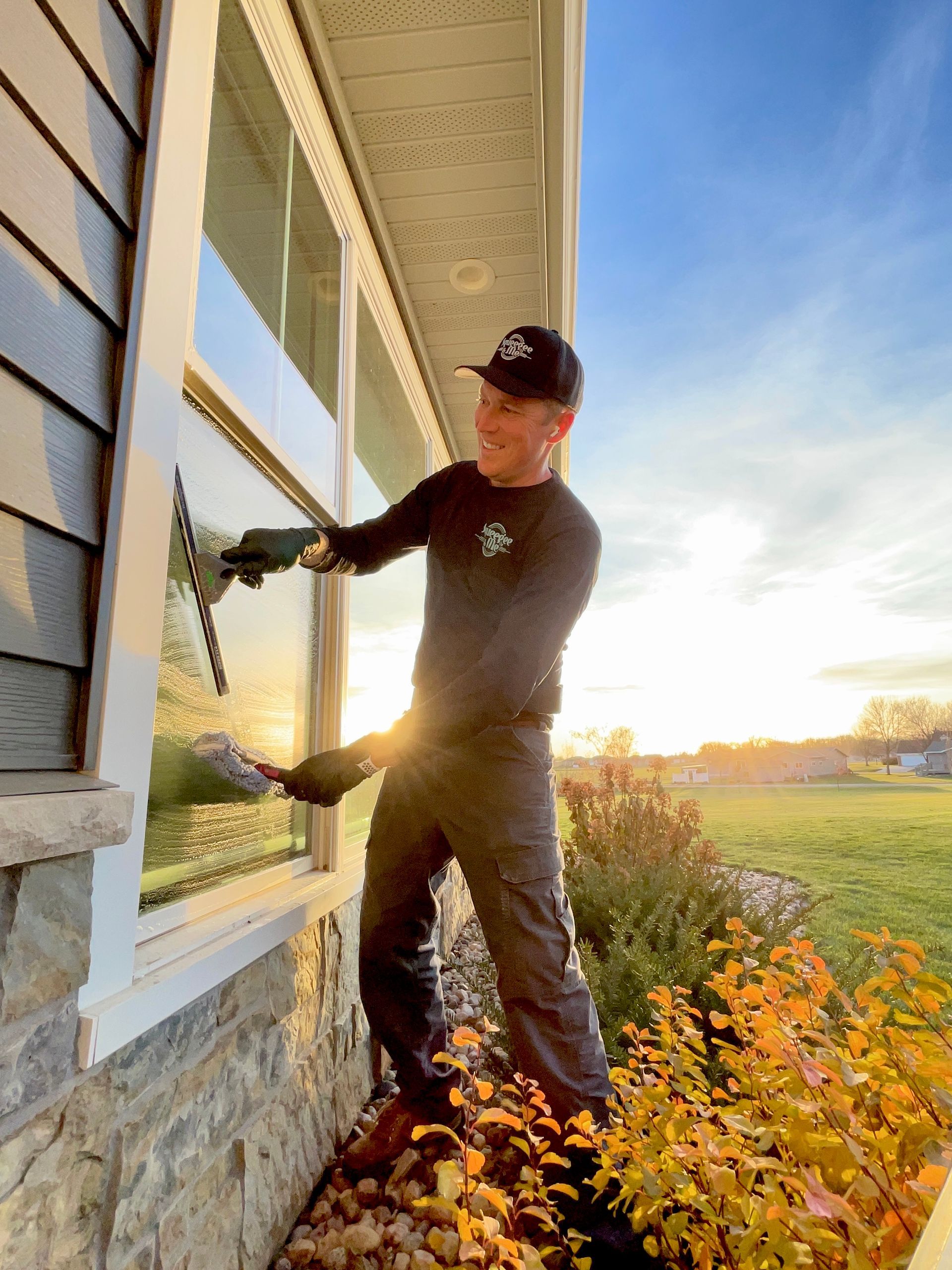 A man is cleaning a window on the side of a house.