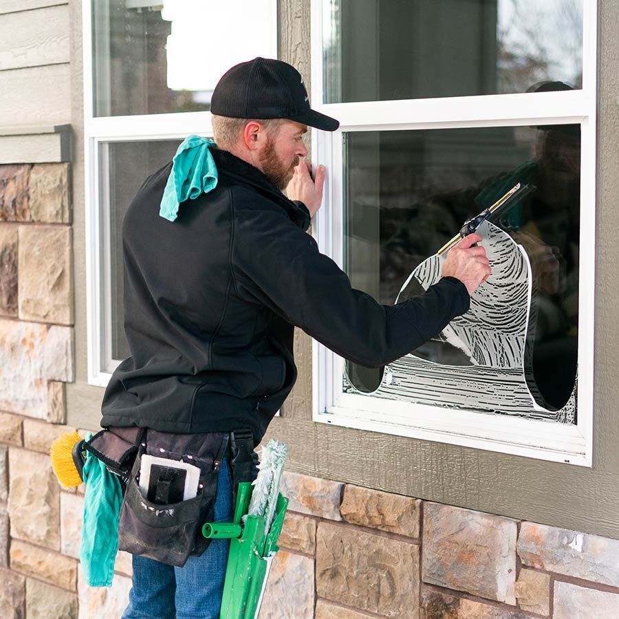 A man is cleaning a window with a mop.