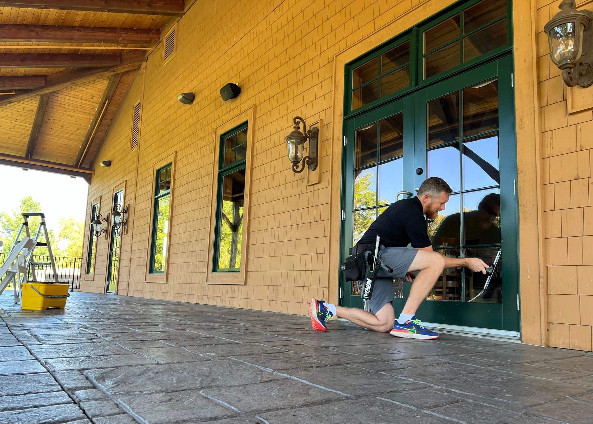 A man is cleaning a green door with a mop.