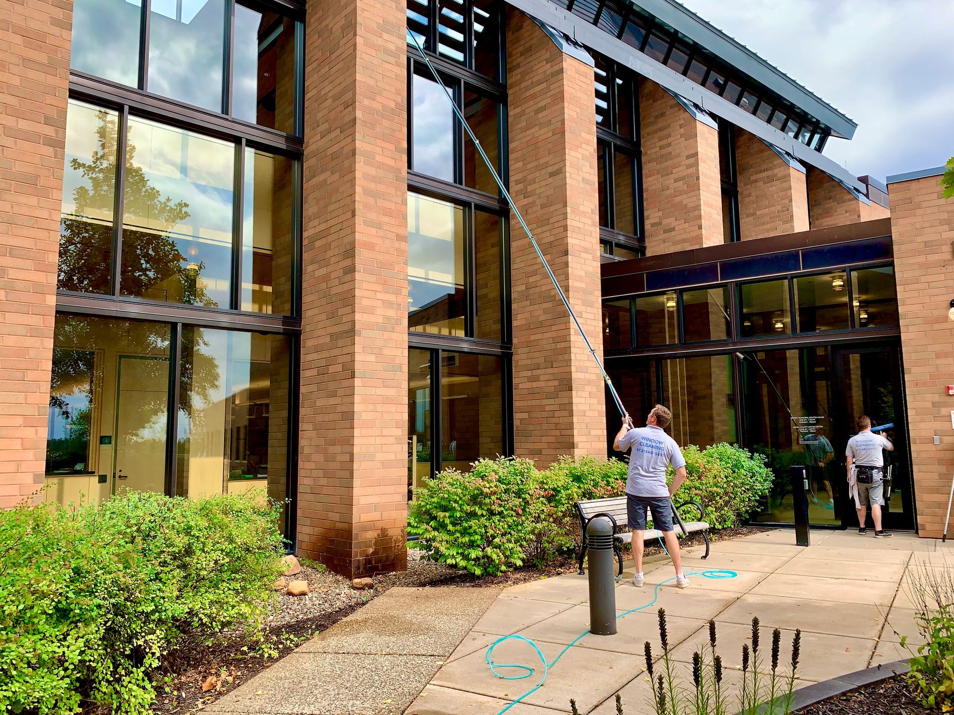 A man is cleaning the windows of a large brick building.