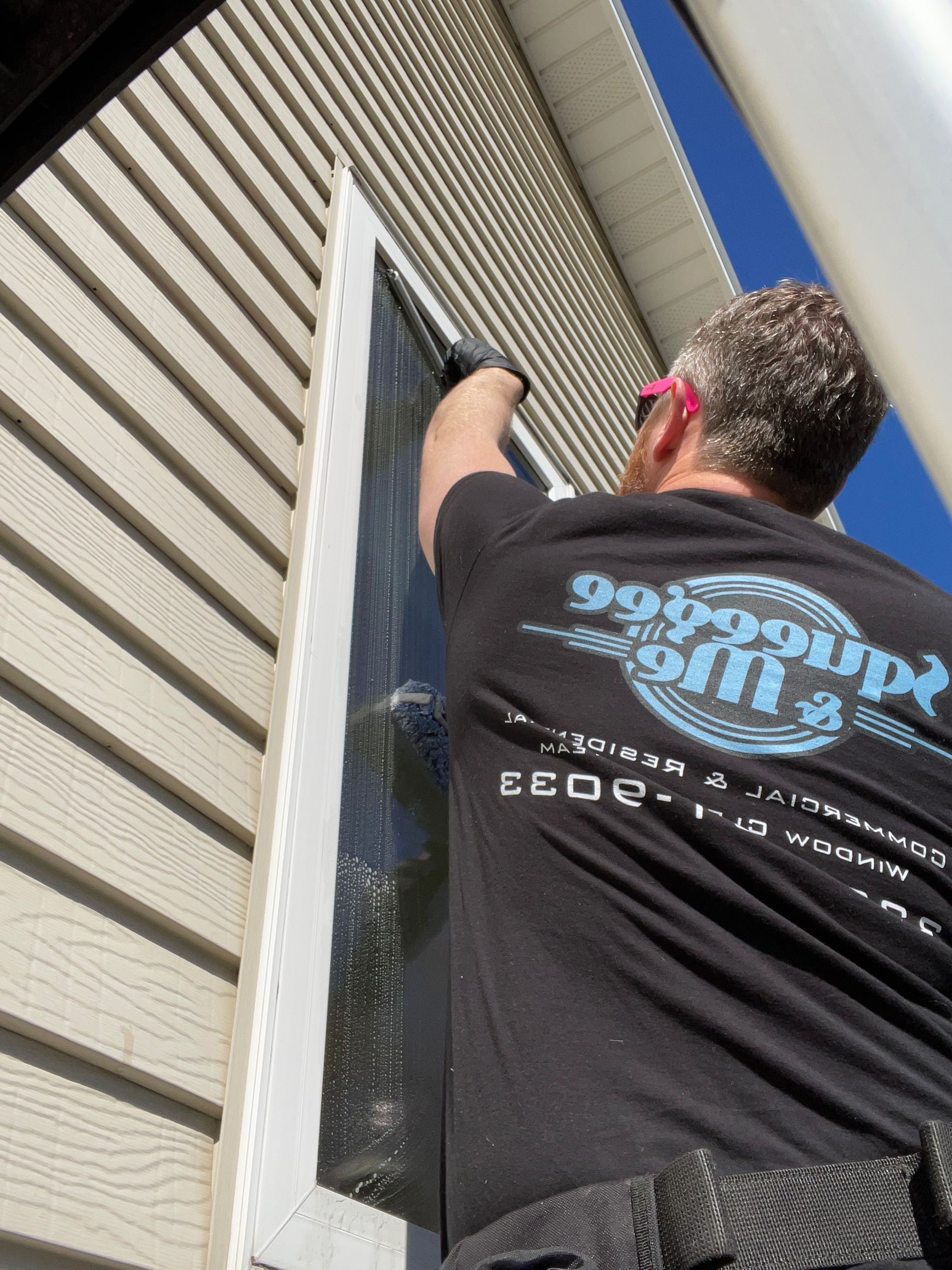 A man wearing a shirt that says 99 percent off is cleaning a window