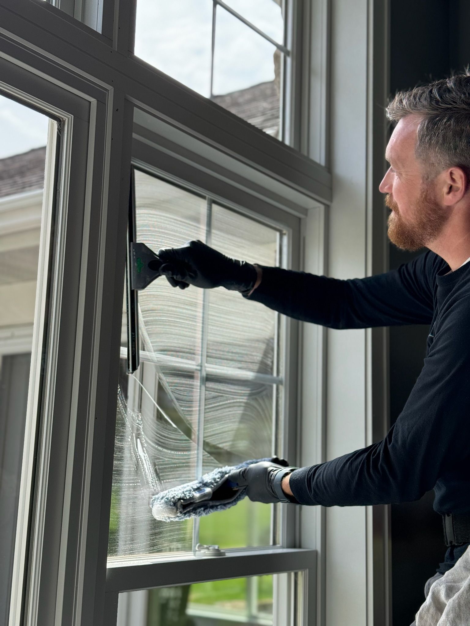 A man is cleaning a window with a brush.