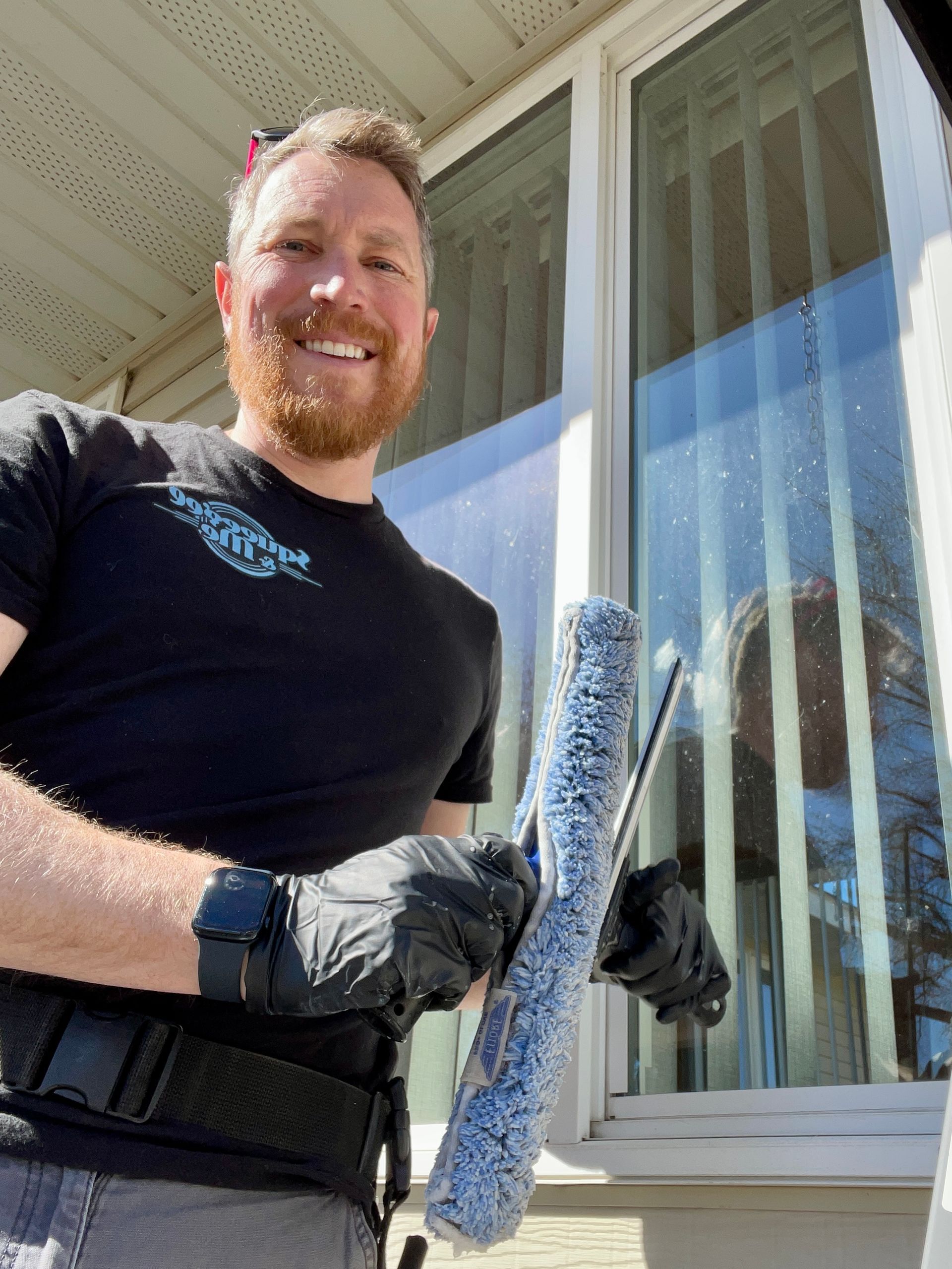 A man is cleaning a window with a mop.