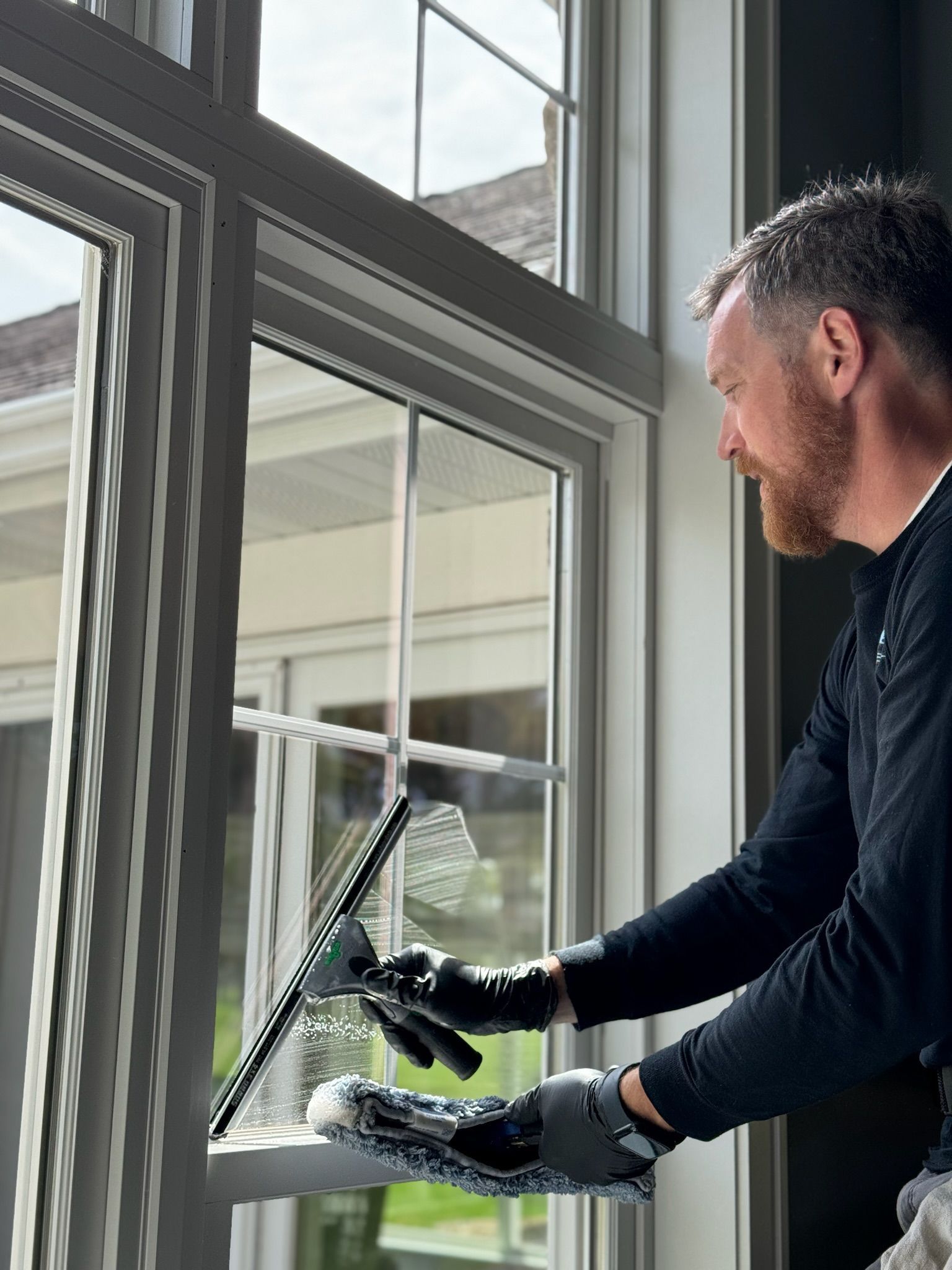 A man is cleaning a window with a squeegee.