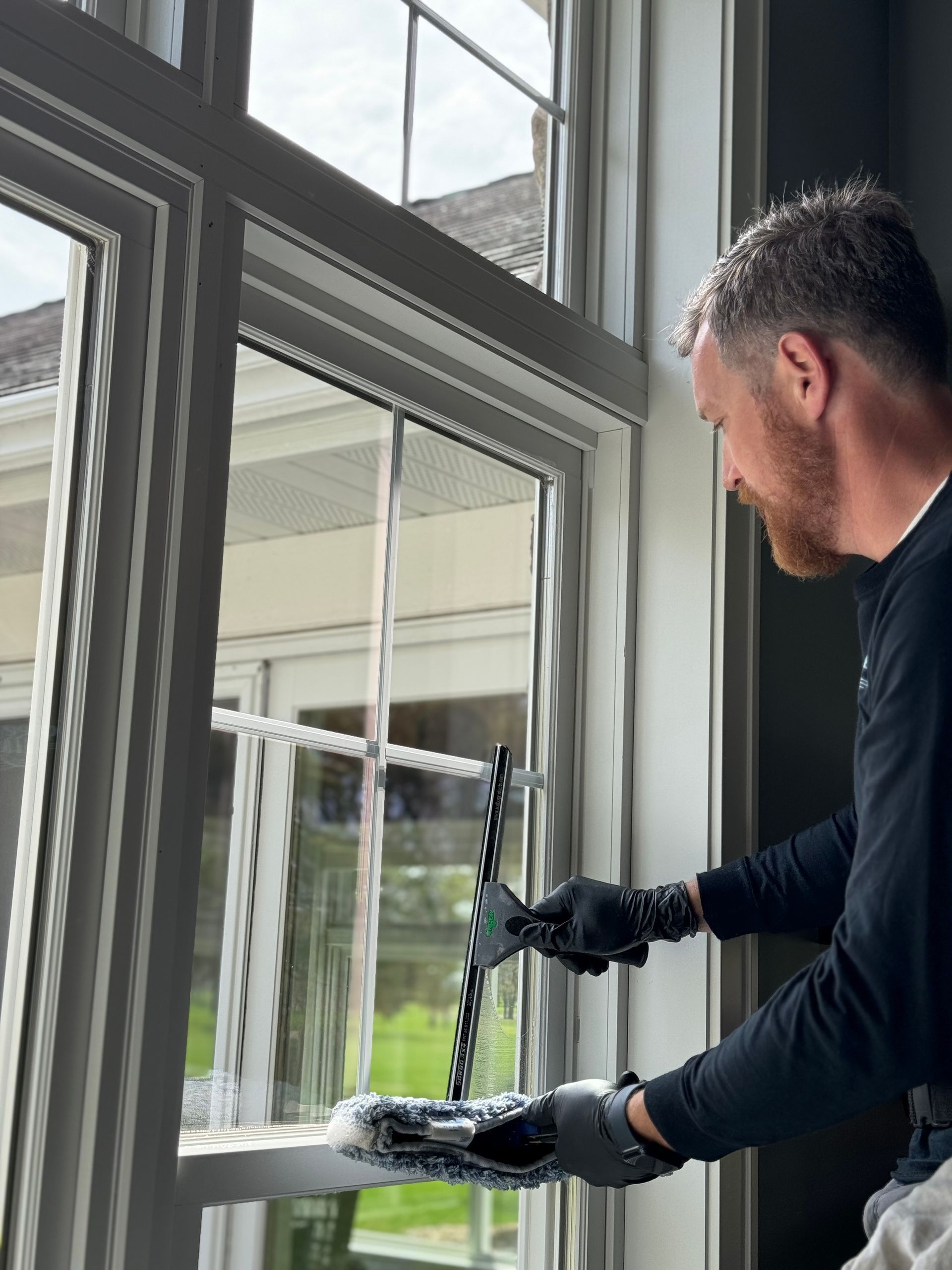 A man is cleaning a window with a mop.
