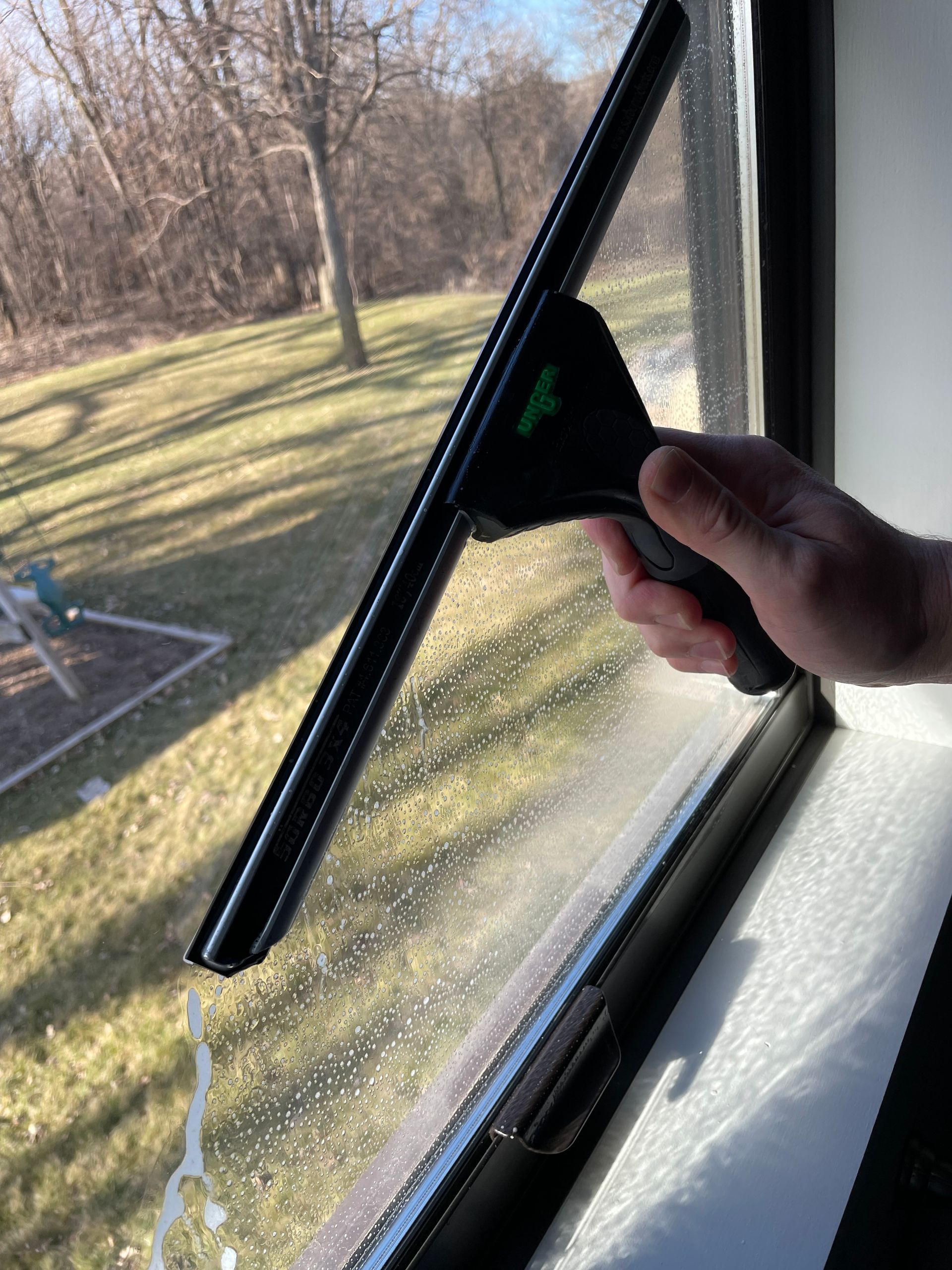 A person is cleaning a window with a squeegee.