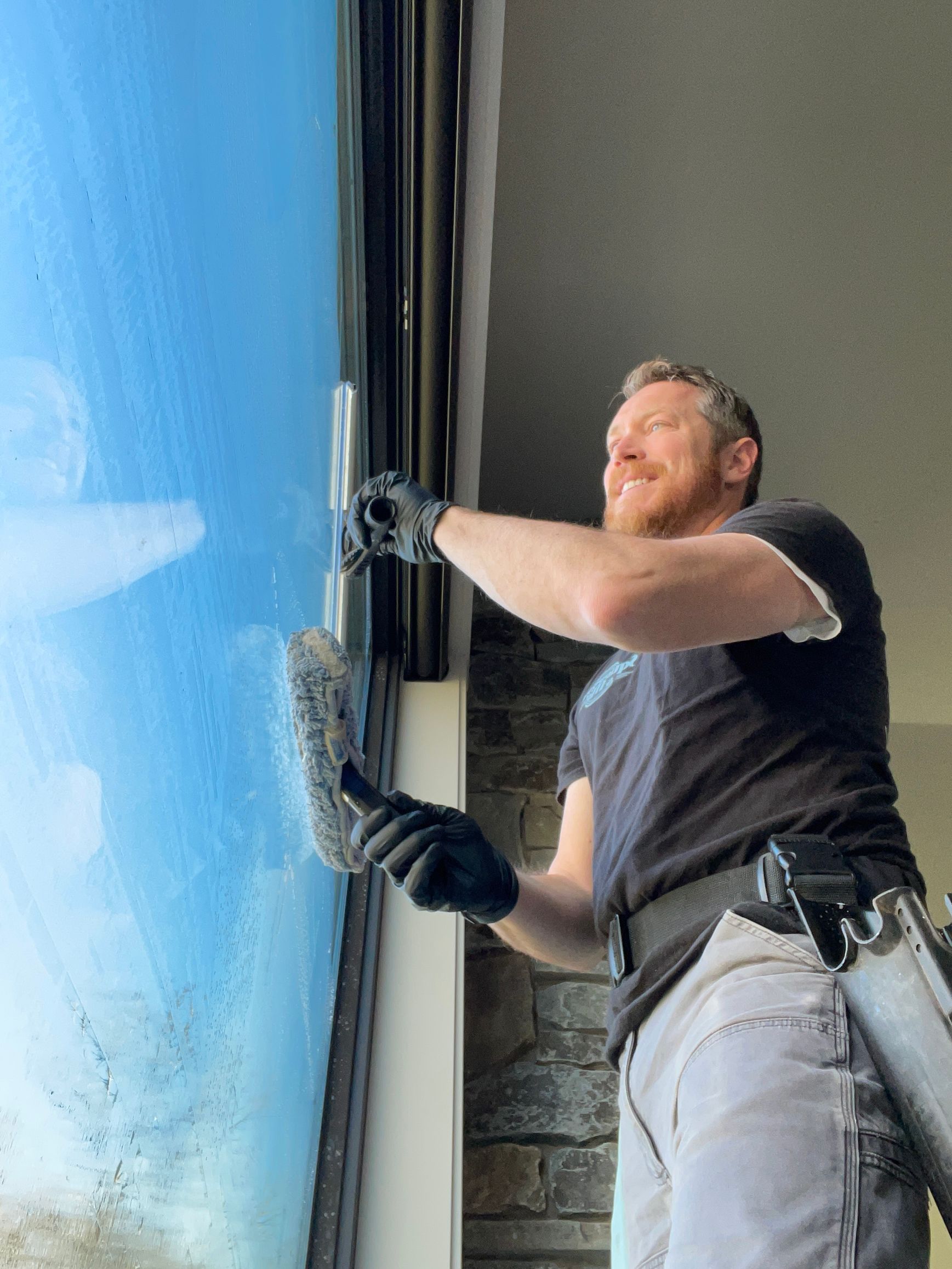 A man is cleaning a window with a sponge.