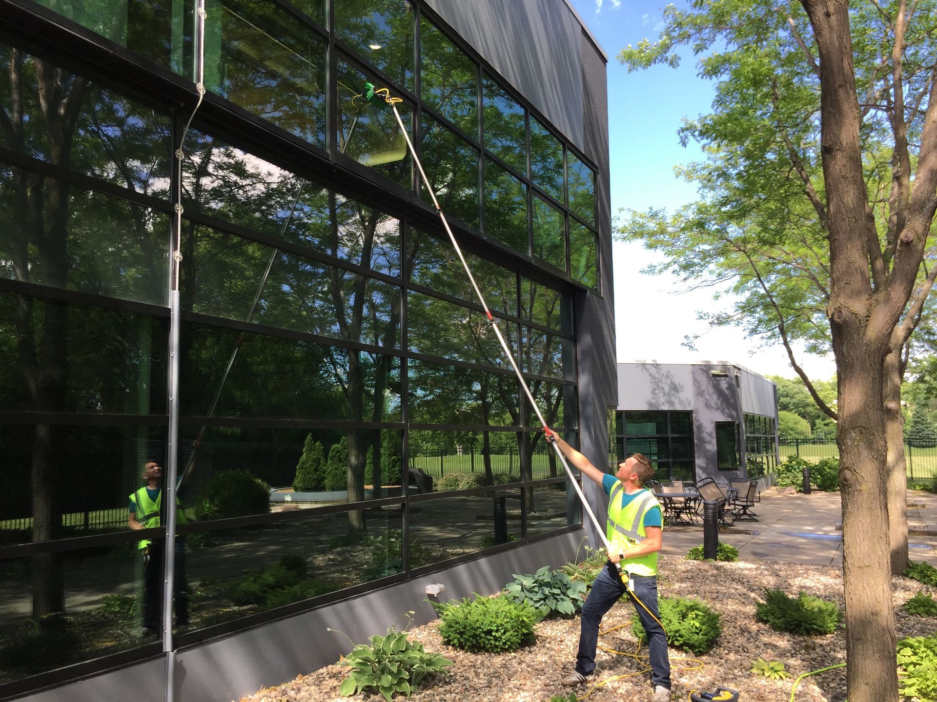 A man is cleaning the windows of a building with a hose.