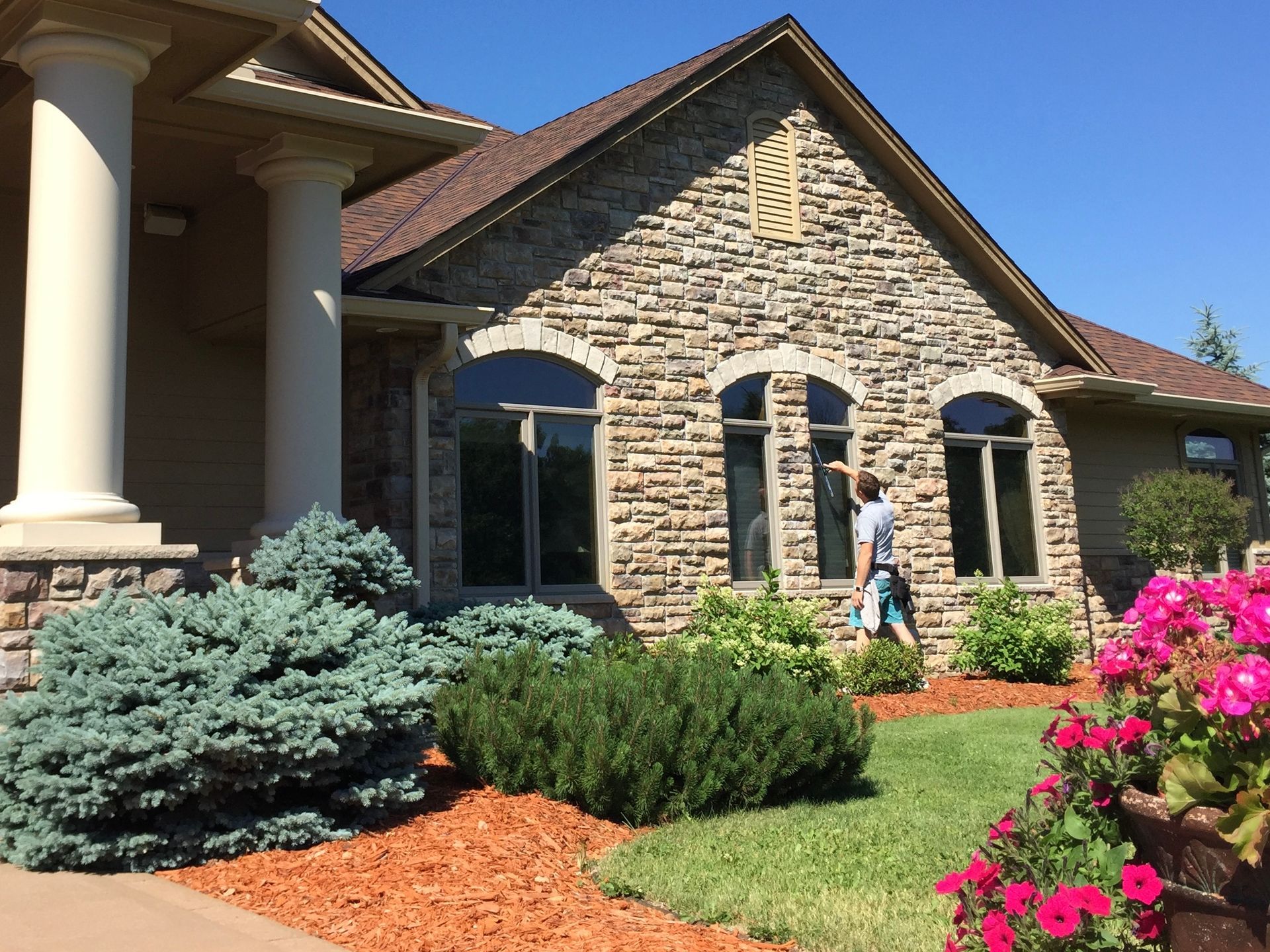 A man is cleaning the windows of a stone house